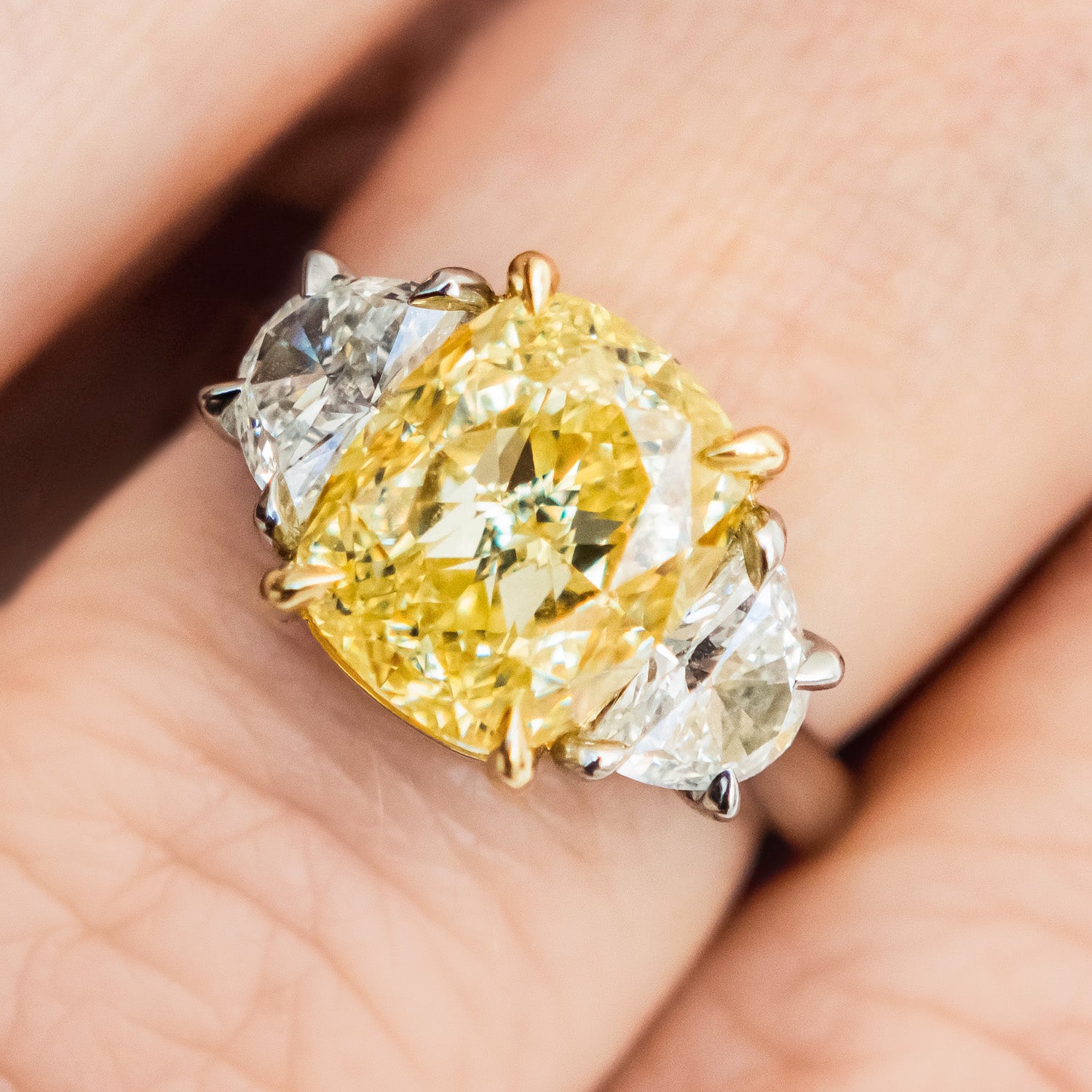 Yellow diamond ring with a pear-shaped center stone on a hand