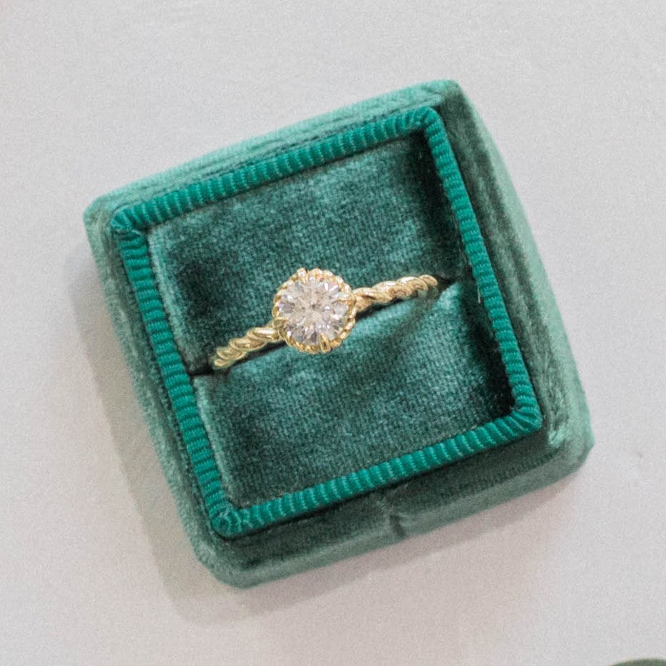 diamond ring in a green box on a white surface
