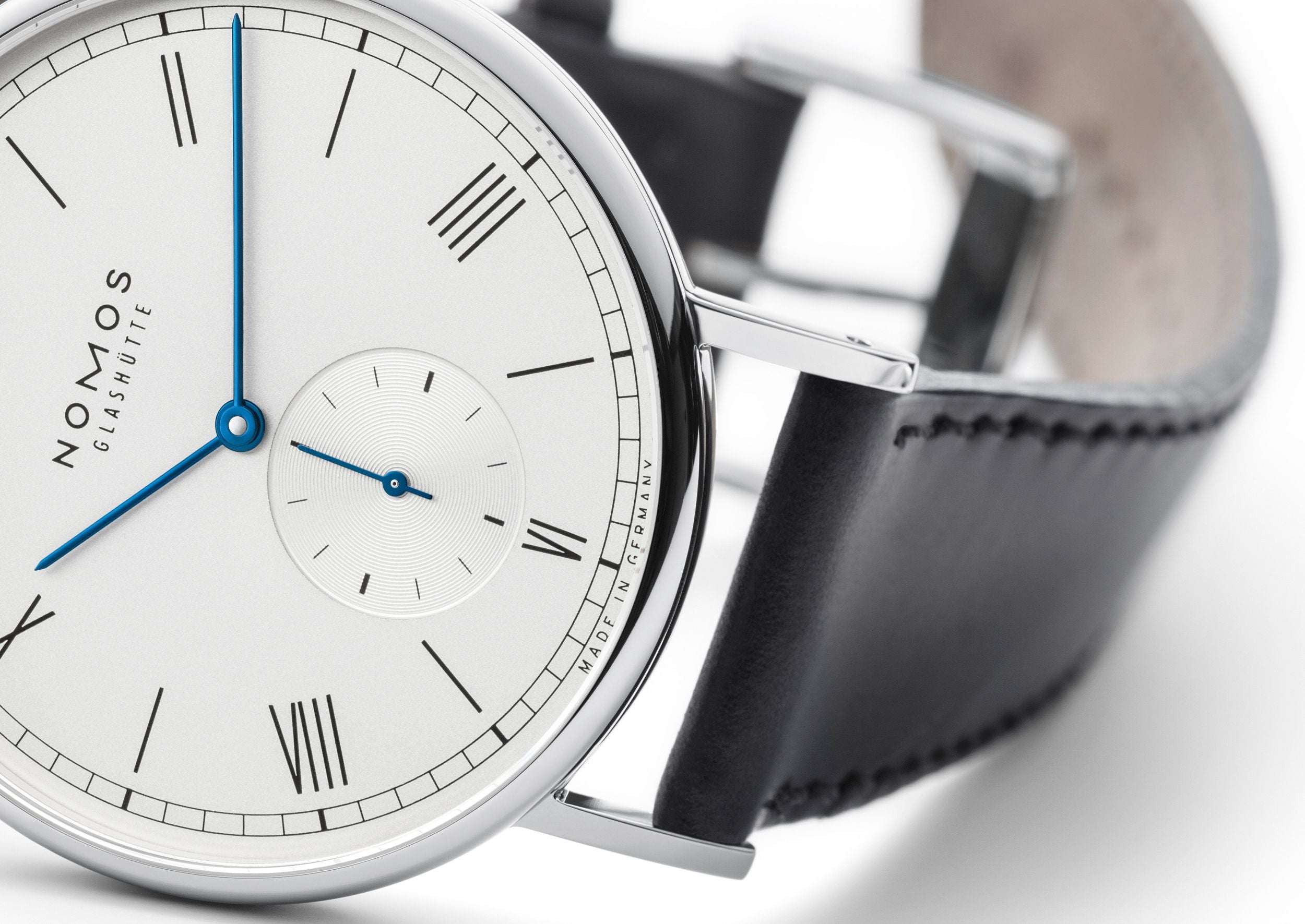 Nomos watch with black leather strap on a white background
