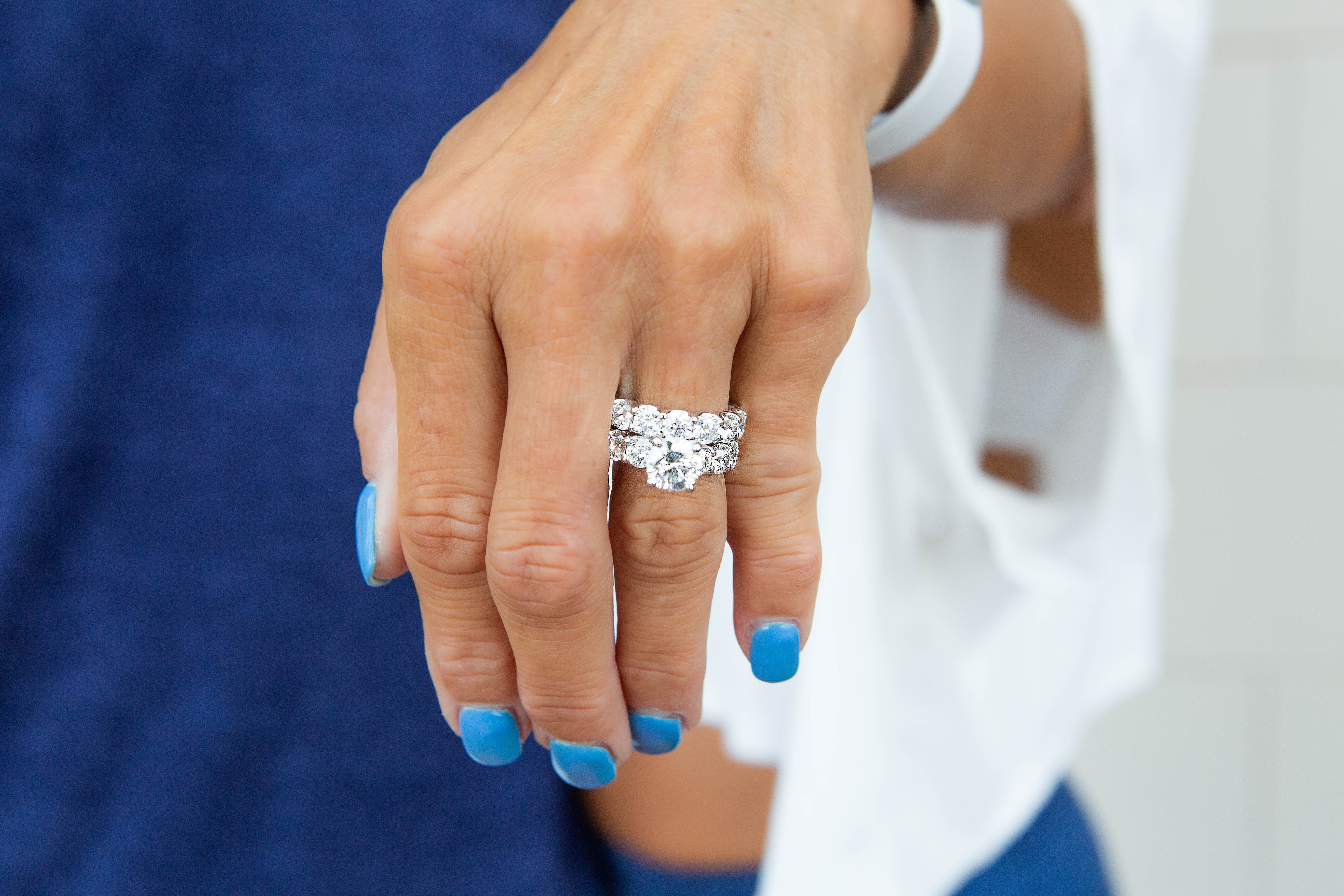Close-up of a hand wearing a diamond ring with a blurred background
