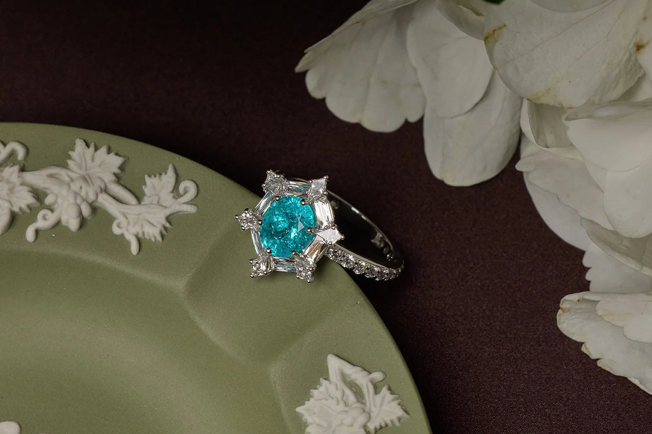 Ring with a blue gemstone on a decorative plate with white flowers in the background