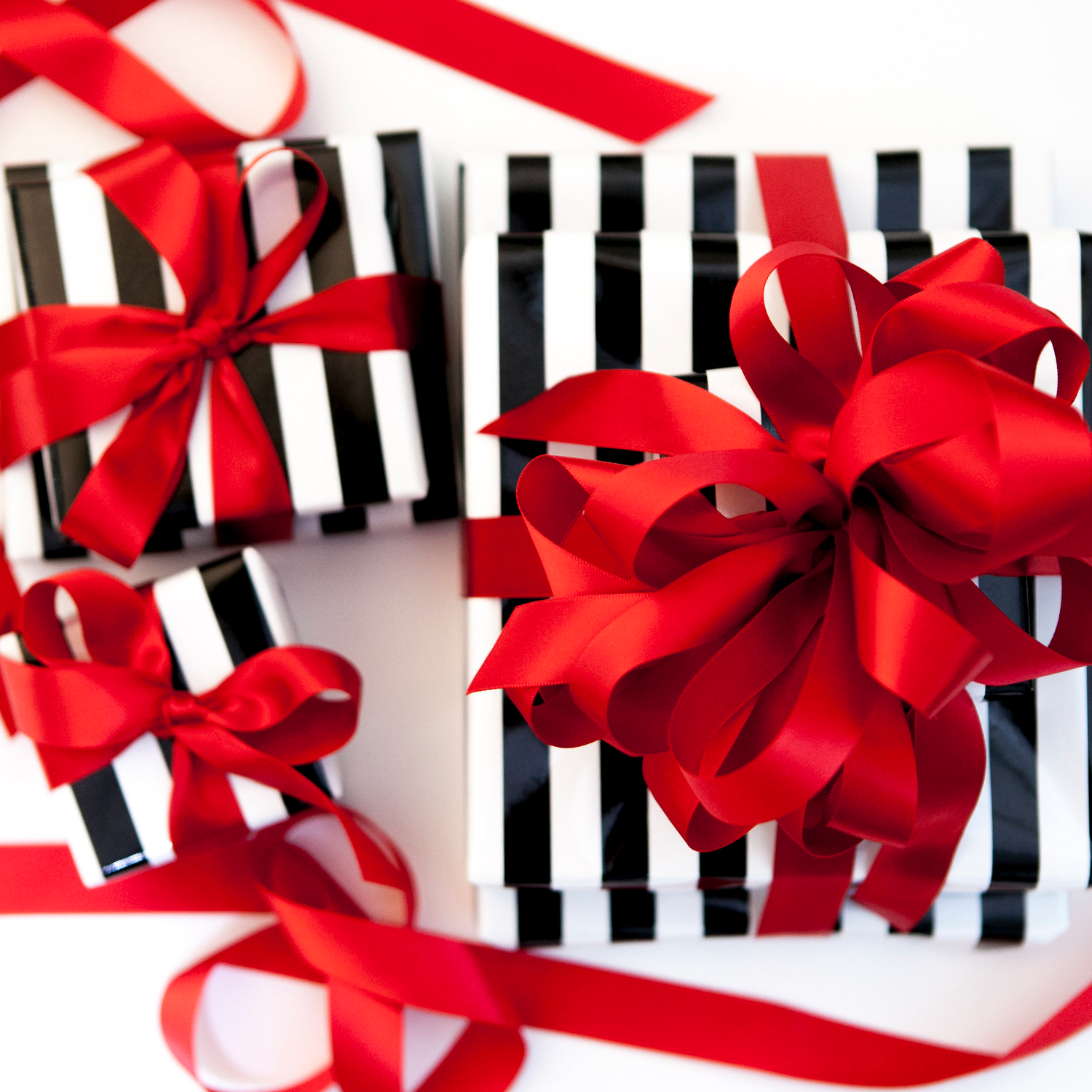 Black and white striped gift boxes with red ribbons on a white background