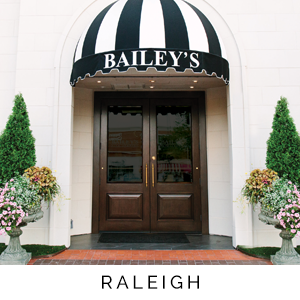 Entrance to a building with a striped awning displaying 'Bailey's' and the word 'Raleigh'.