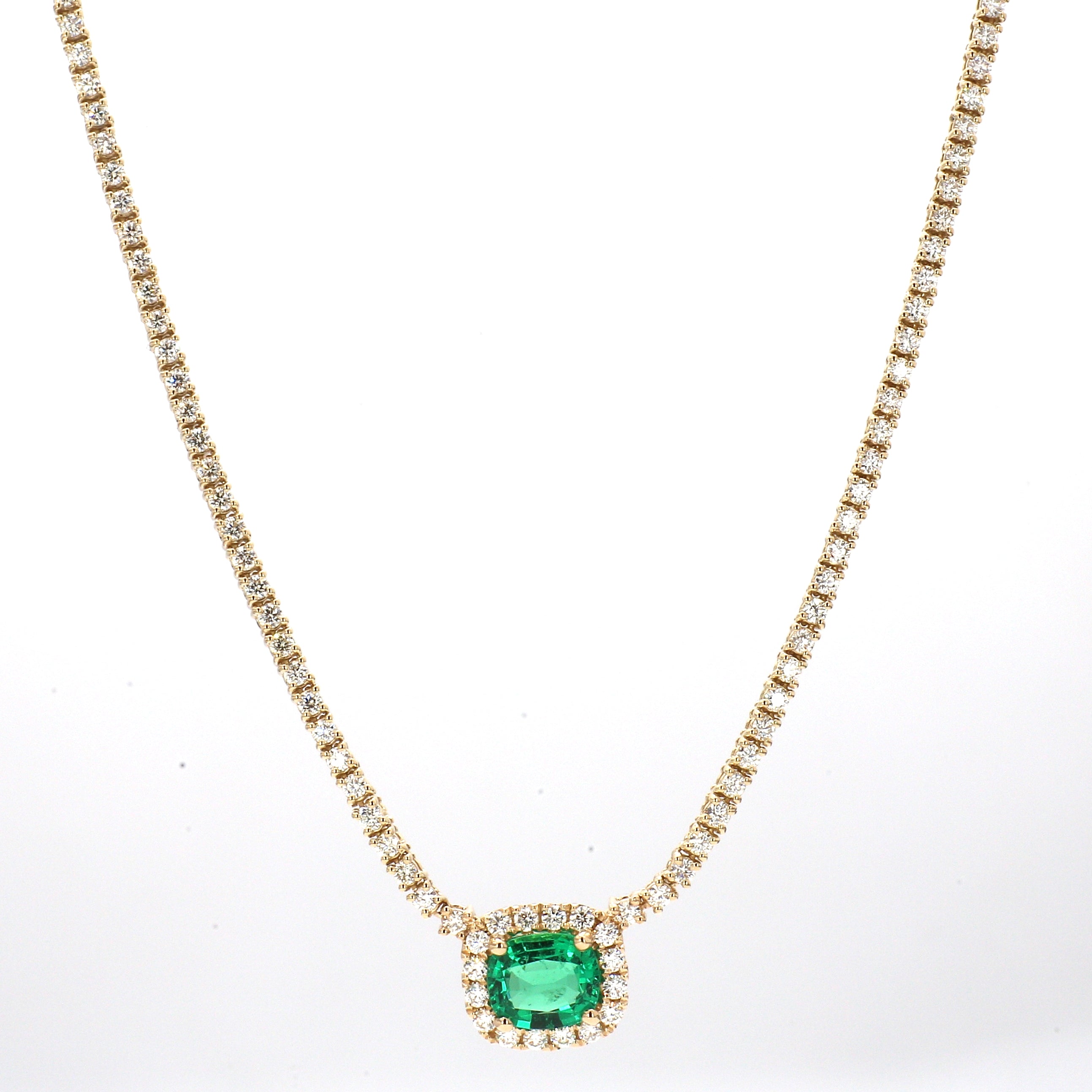Gold necklace with emerald center stone and diamonds on a white background