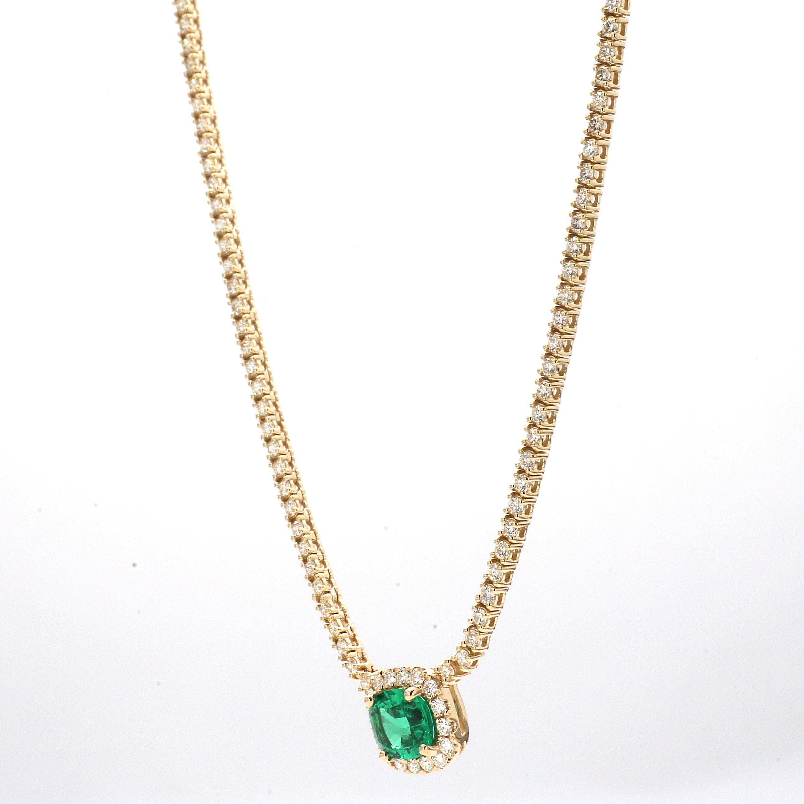 Gold necklace with emerald center stone and diamonds on a white background