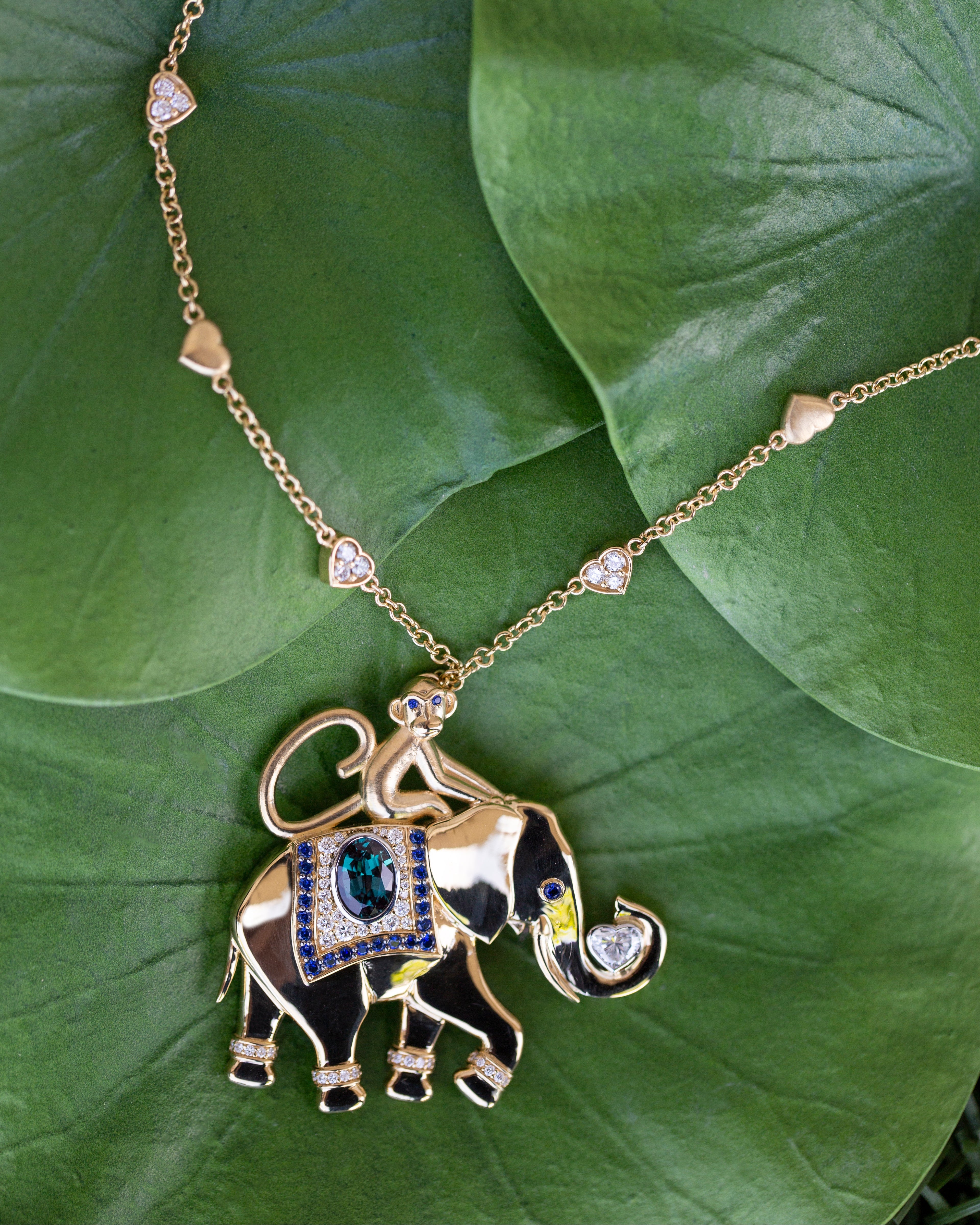 Gold elephant pendant necklace on a green leaf background