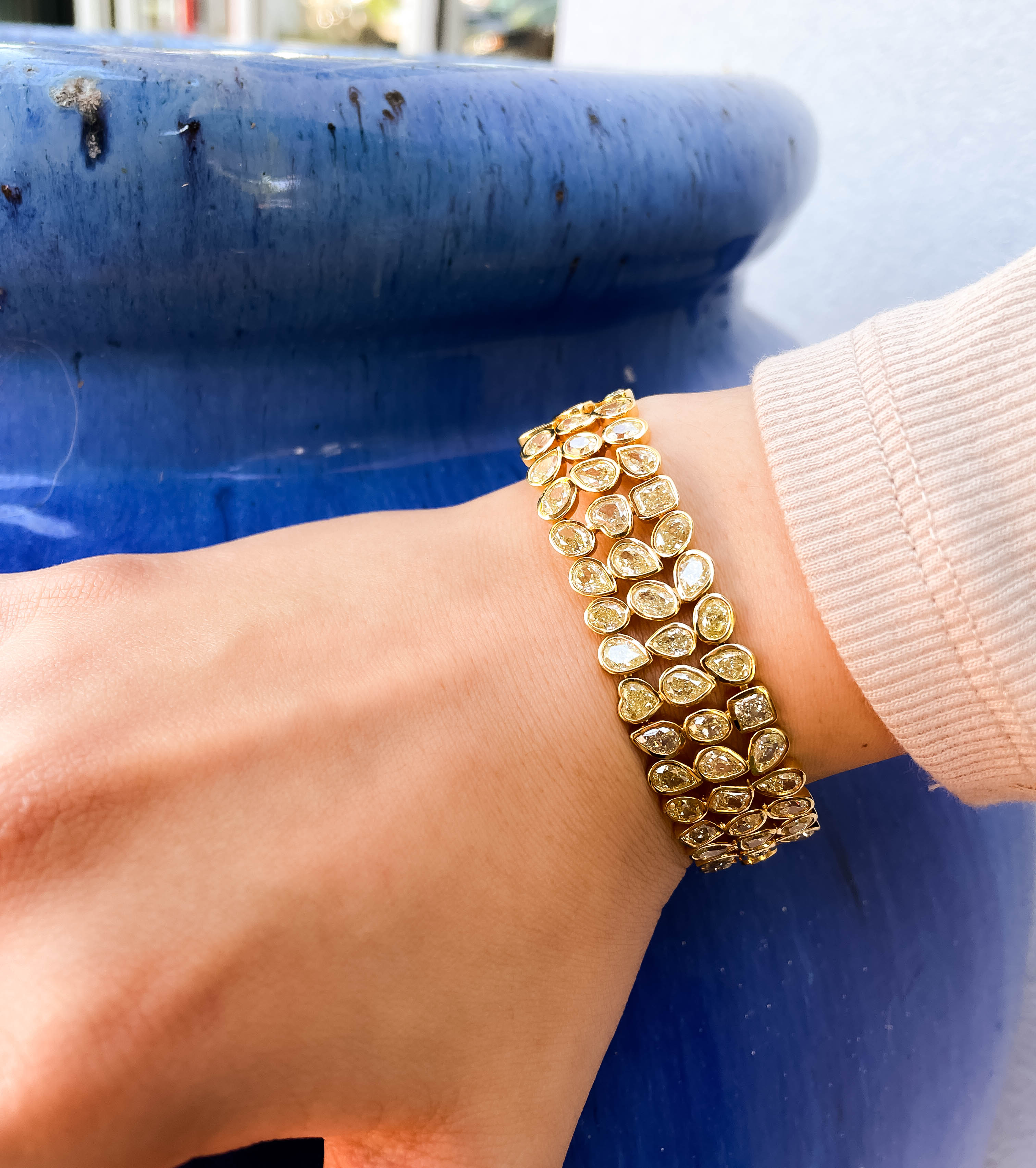 Gold bracelet on a wrist with a blue background
