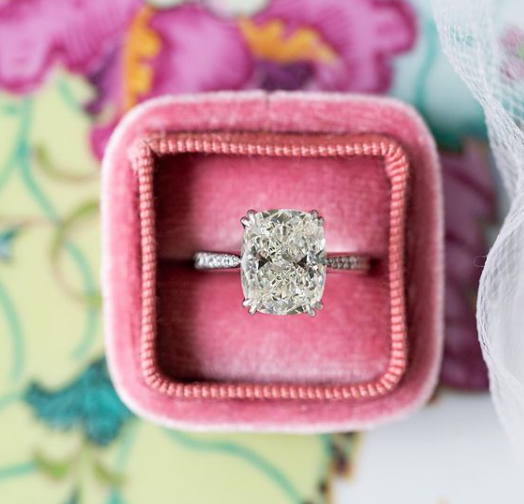 Diamond ring in a pink velvet box on a floral background