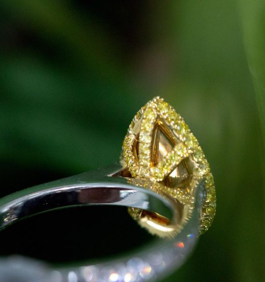 close up of yellow diamond ring on green leaf background