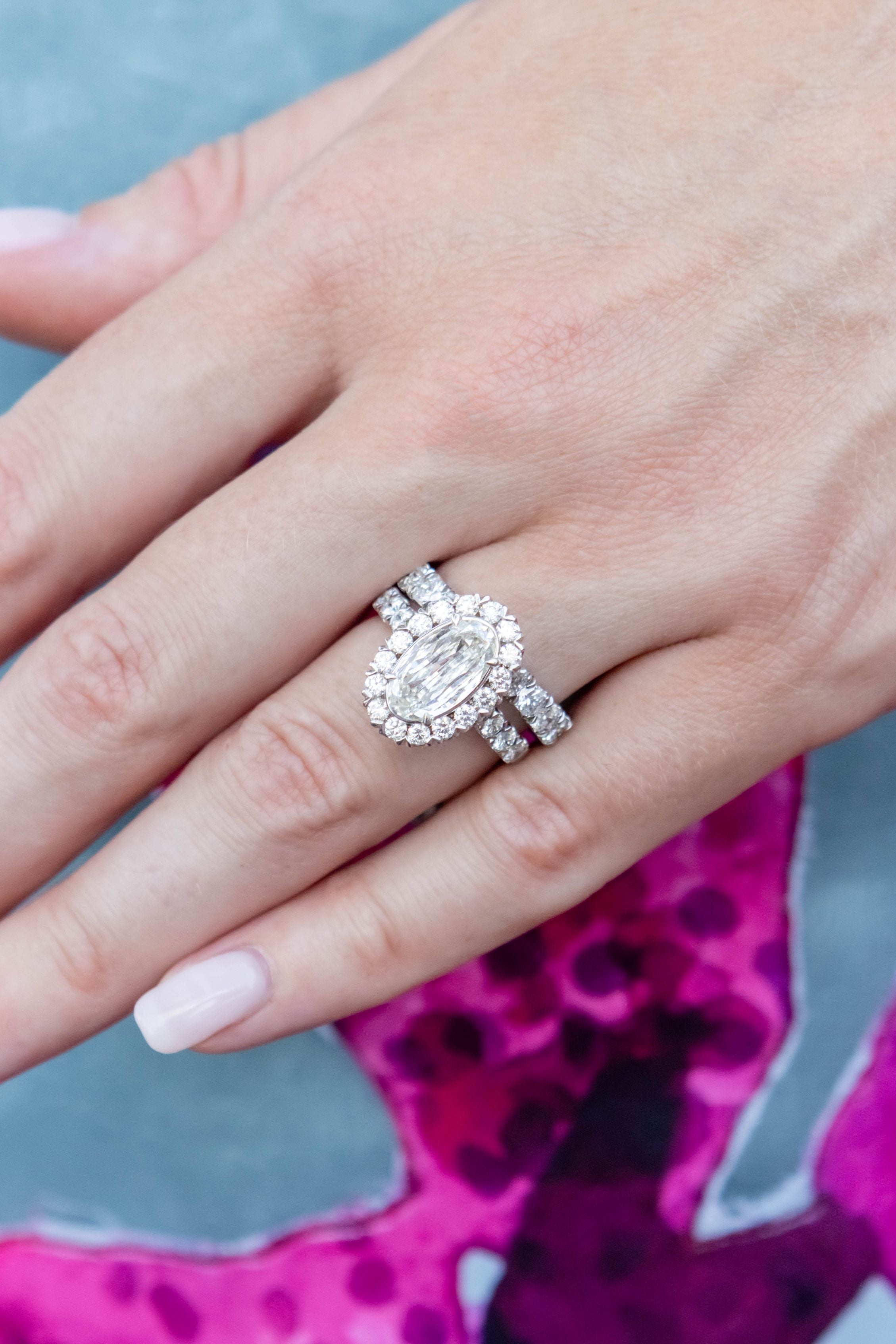 Close-up of a hand wearing a diamond ring with a blurred blue and purple background