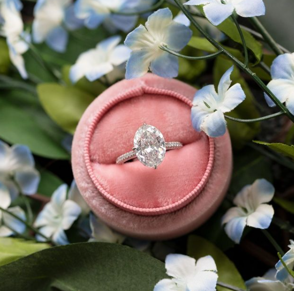 Diamond ring on a pink velvet cushion surrounded by flowers