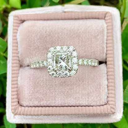 Diamond ring in a pink velvet box with green leaves in the background