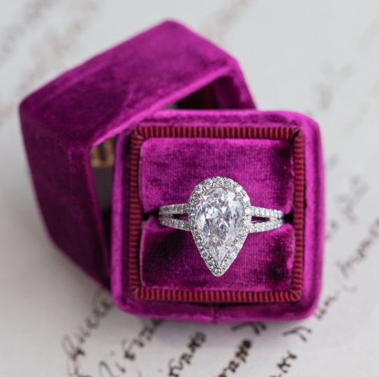 Diamond ring in a purple velvet box on a textured surface