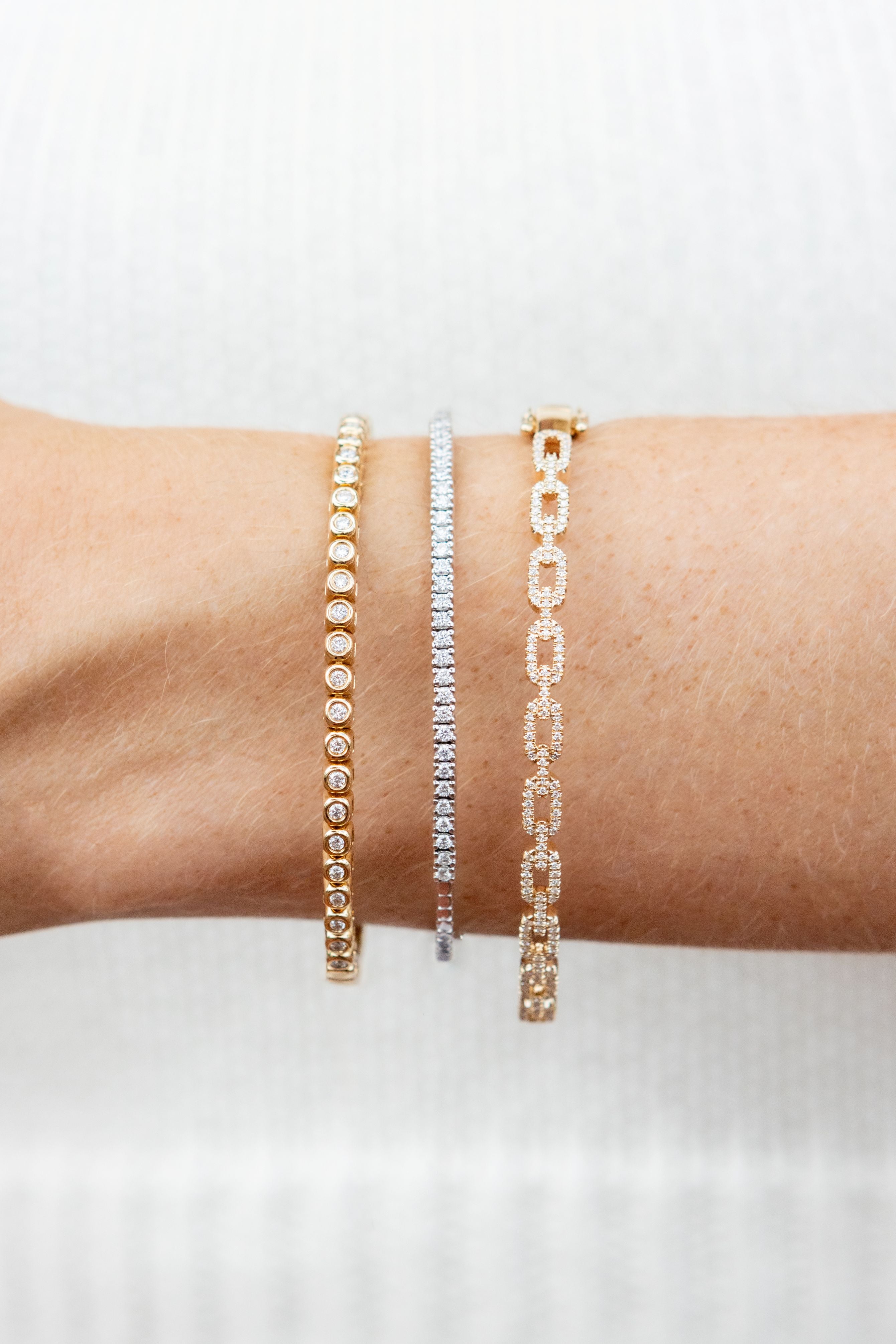 Three bracelets on a person's wrist against a white background
