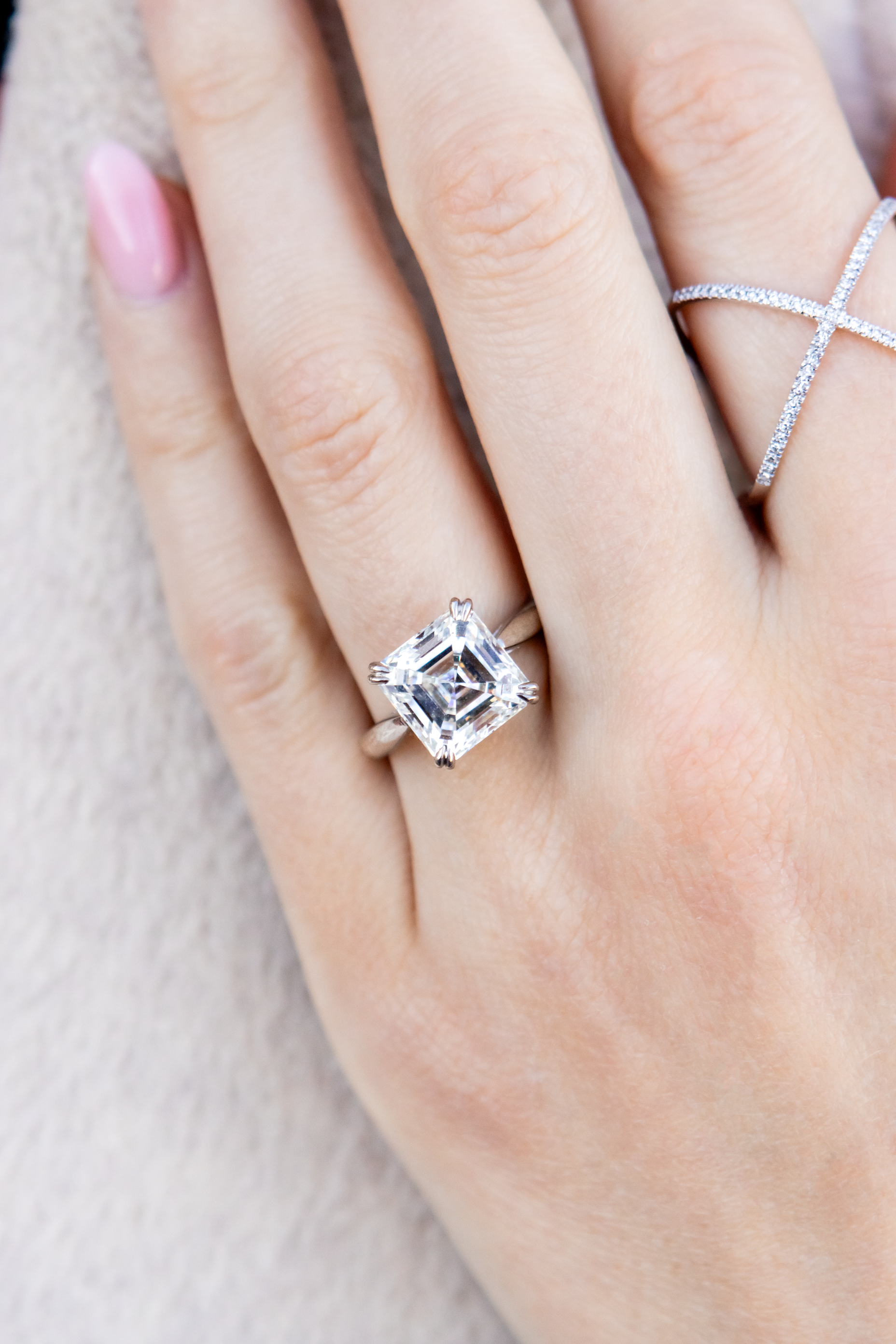 hand wearing diamond rings on a white fuzzy background