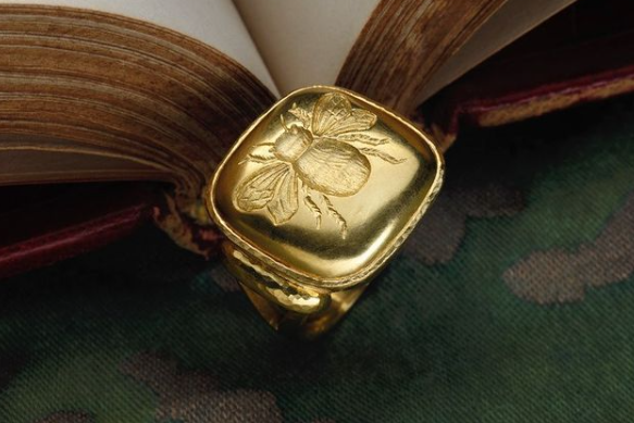 Gold ring with a beetle design on an open book