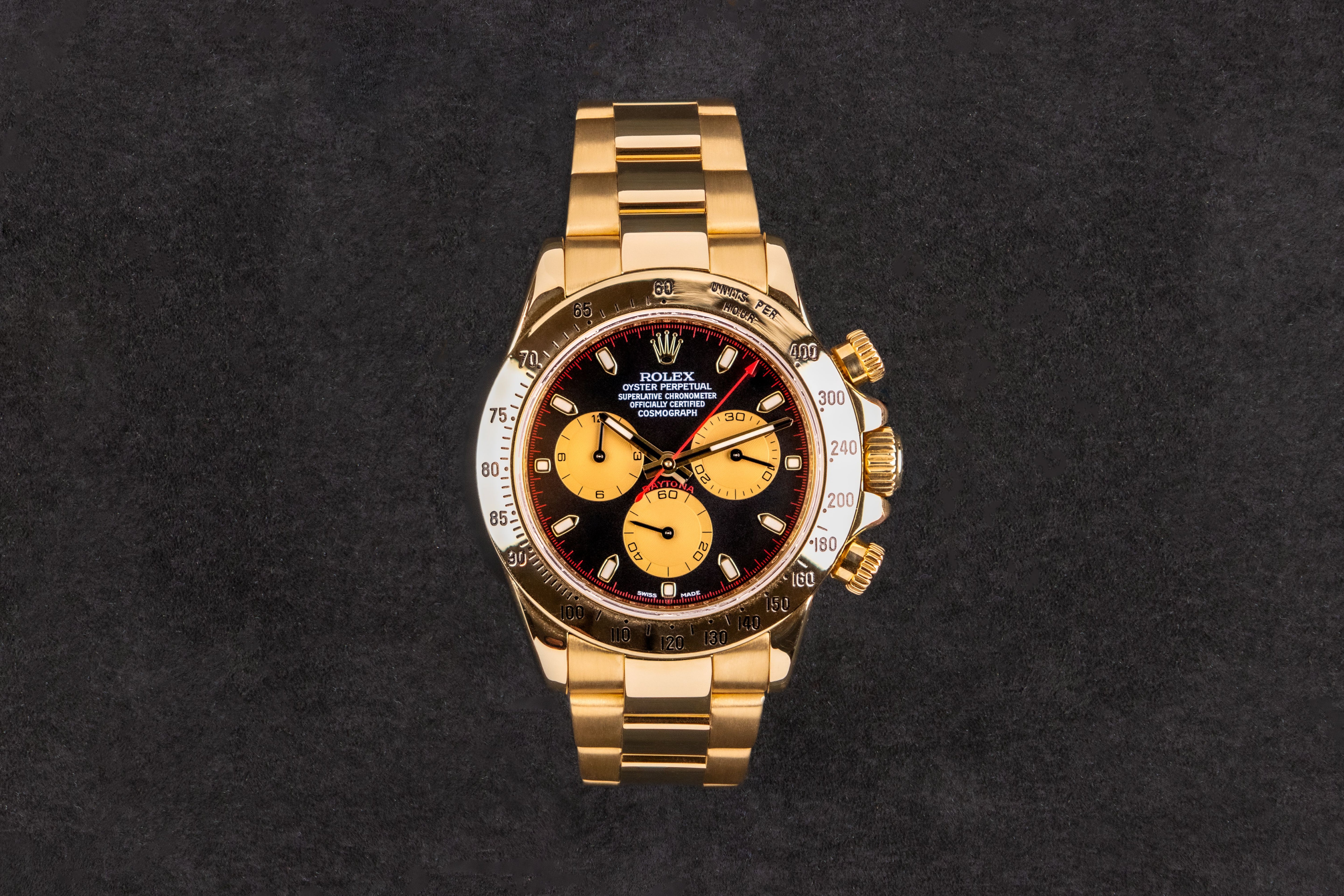 Gold wristwatch with a black face on a dark background