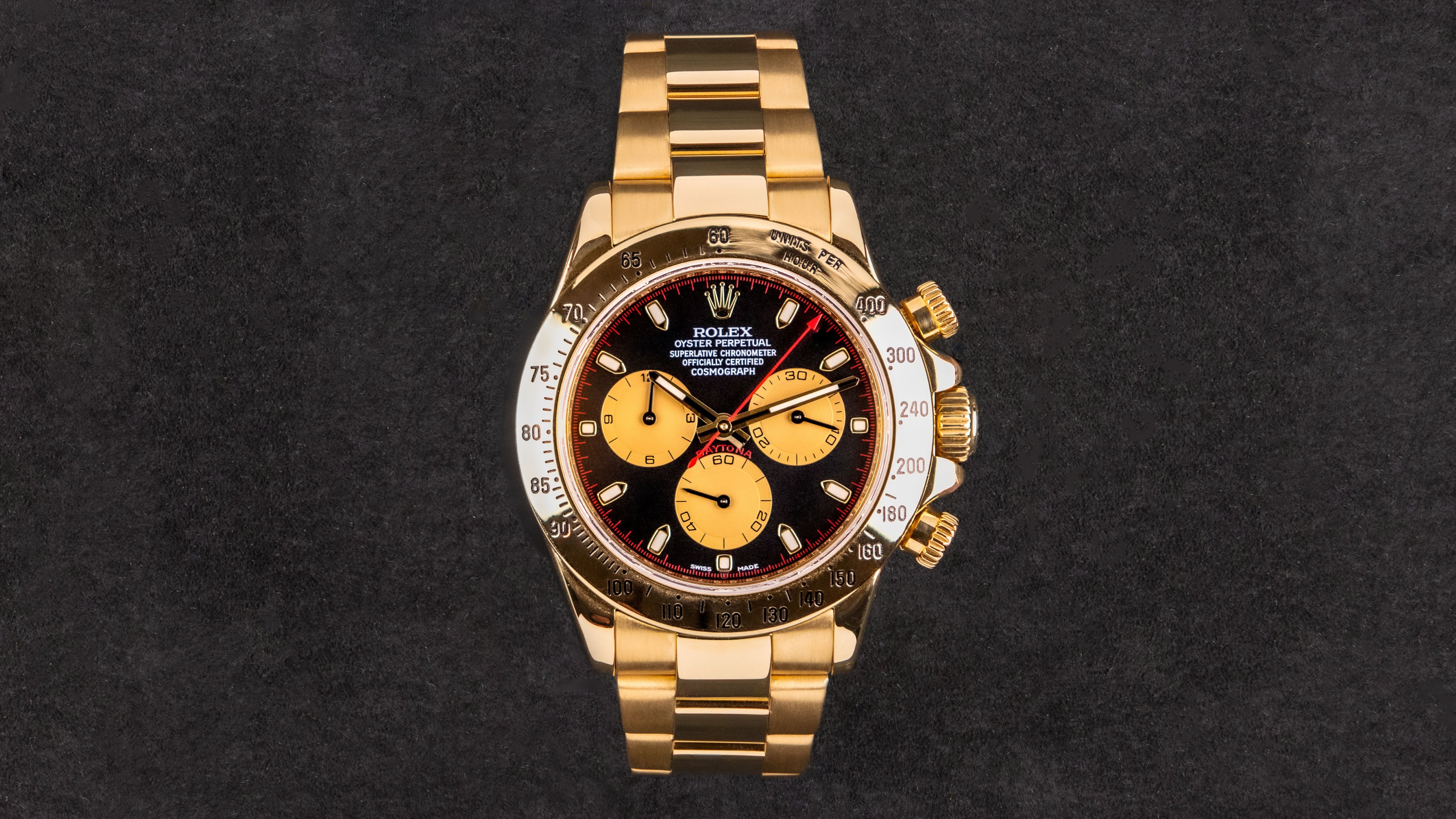 Gold wristwatch with a black face on a dark background