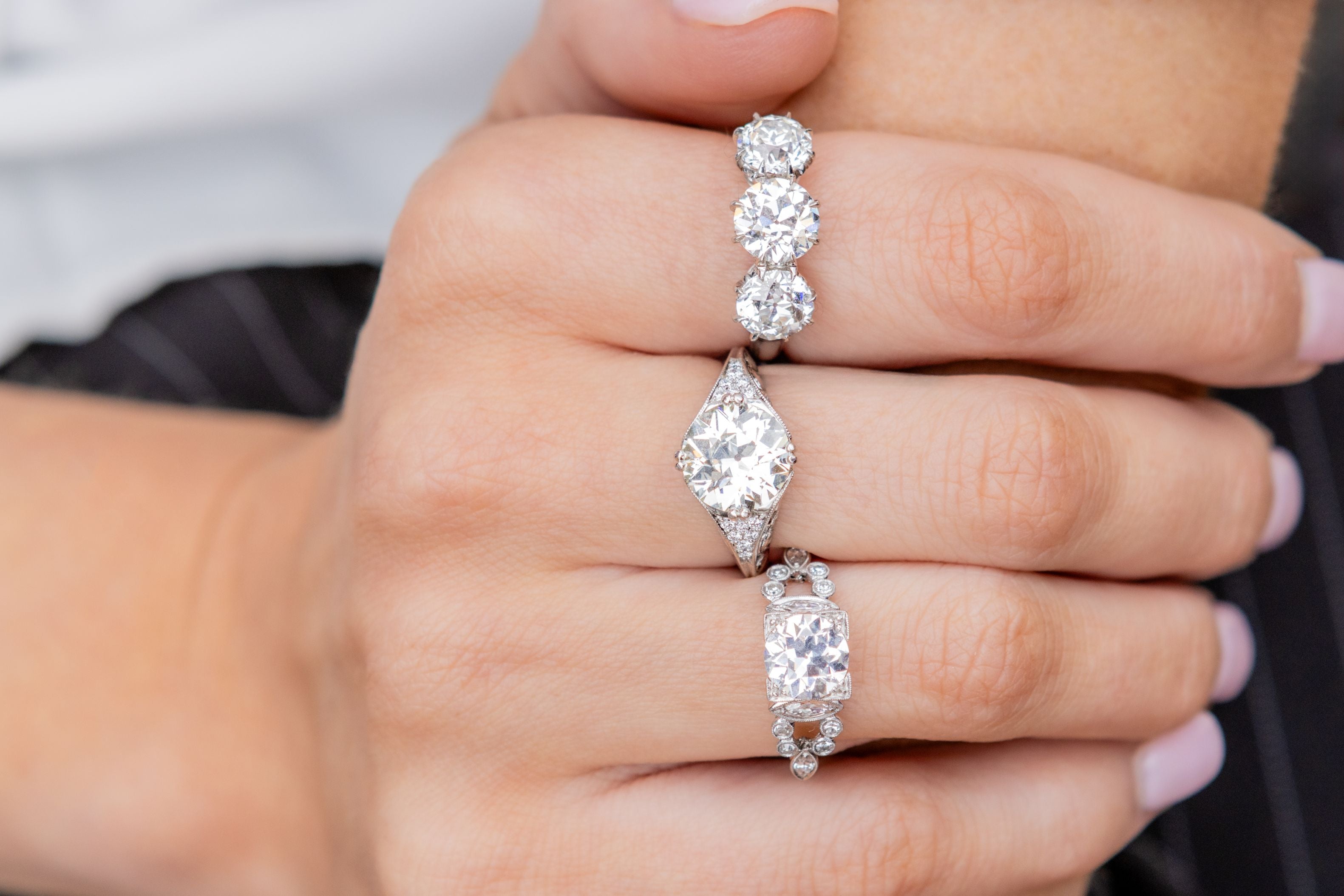 Close-up of a hand wearing three diamond rings on different fingers.