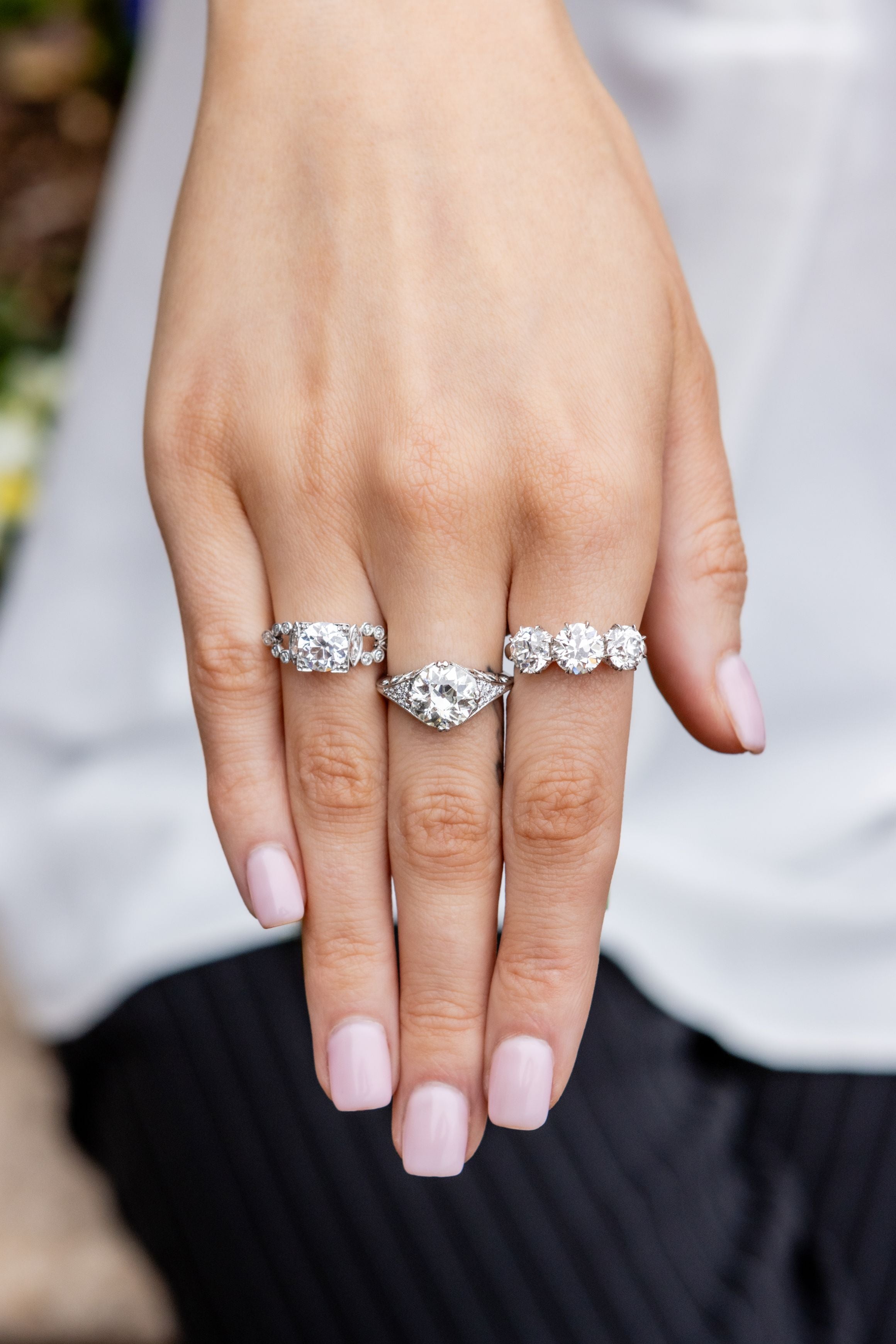 hand wearing three diamond rings with blurred black and white background