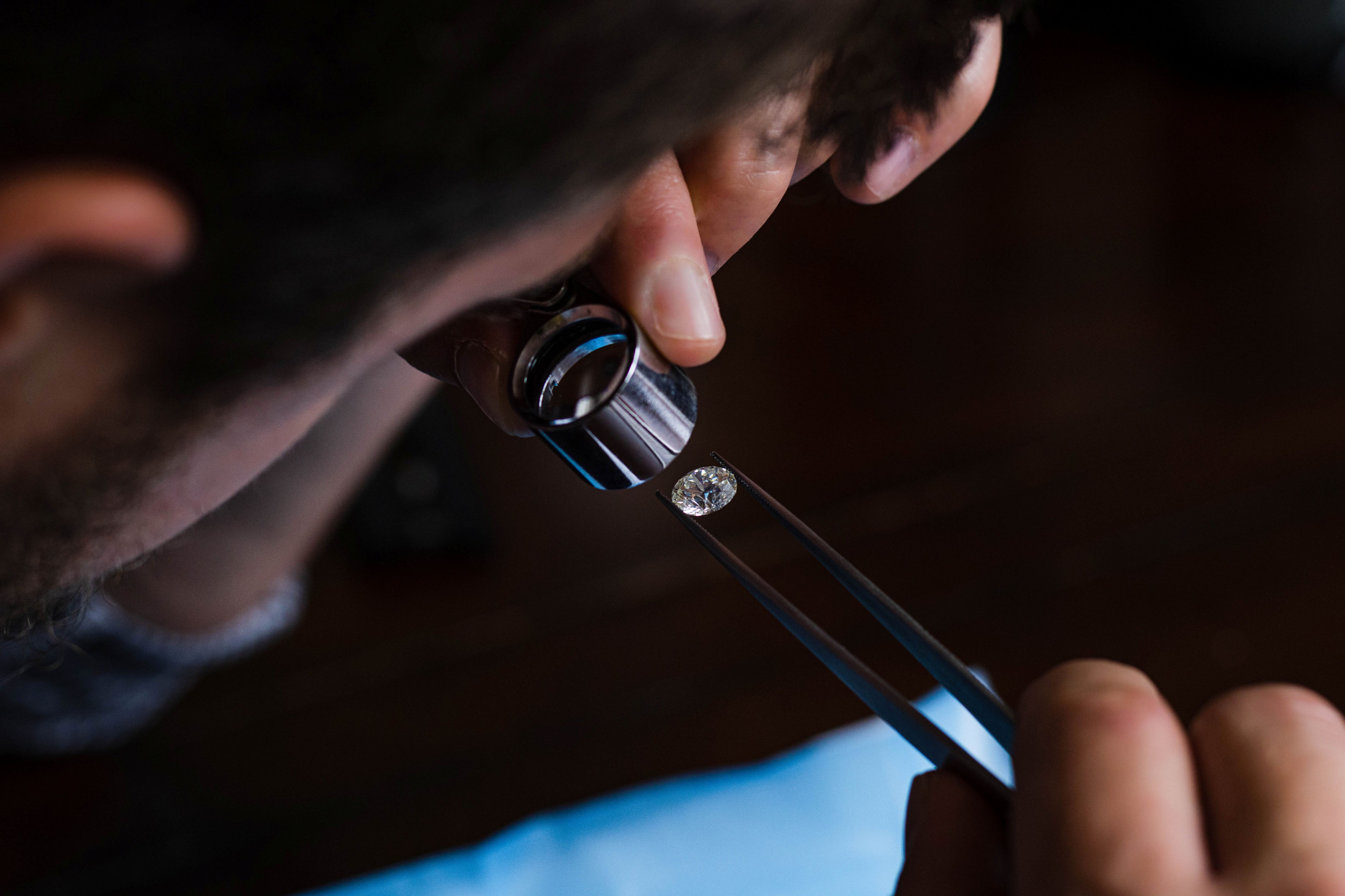 Person using a magnified glass to view diamond on a dark background