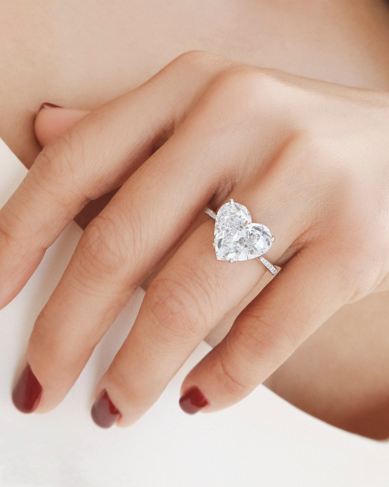hand with heart-shaped diamond silver ring with neutral background