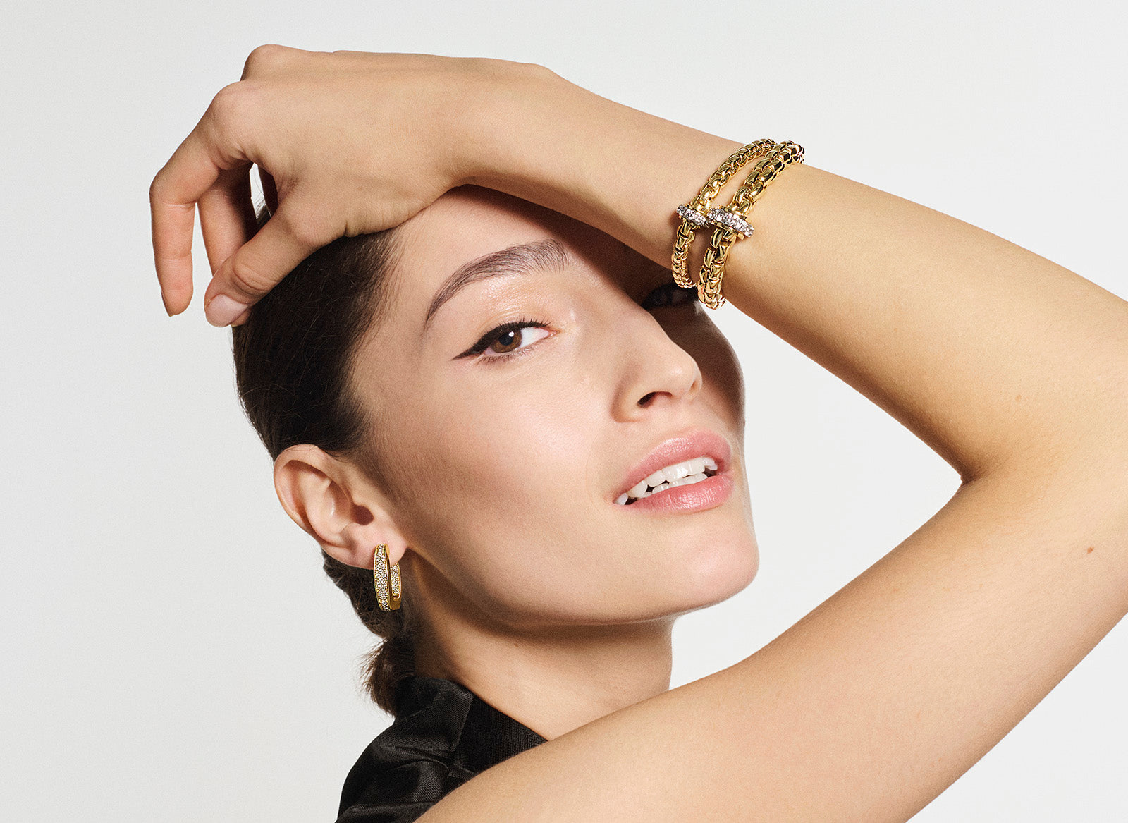 Woman wearing gold jewelry against a white background