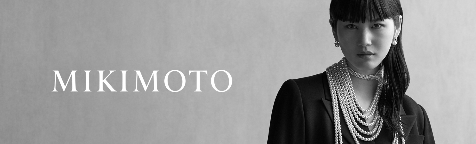 Mikimoto advertisement with a woman wearing pearls against a gray background