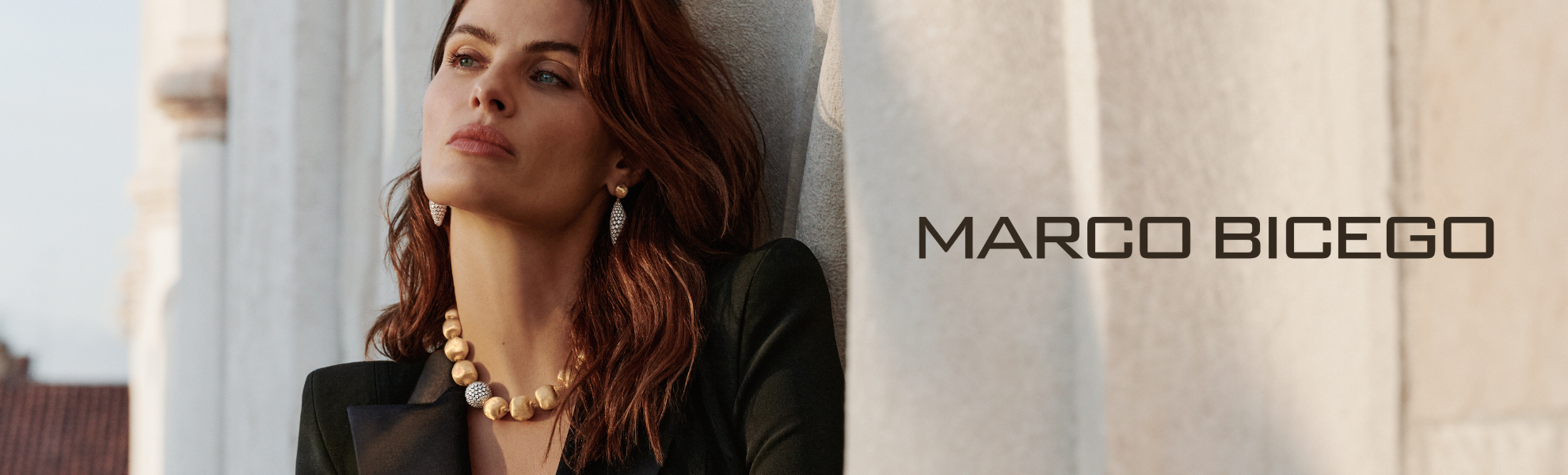Woman wearing a necklace with 'Marco Bicego' branding in the background