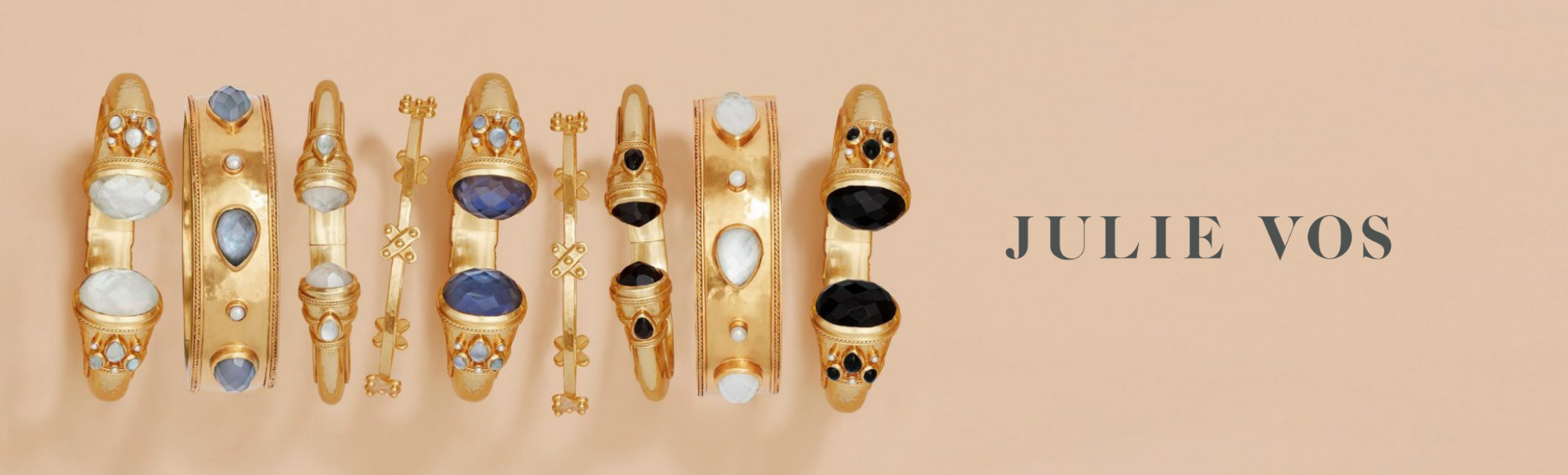 Gold earrings with gemstones on a beige background, featuring the brand 'Julie Vos'.