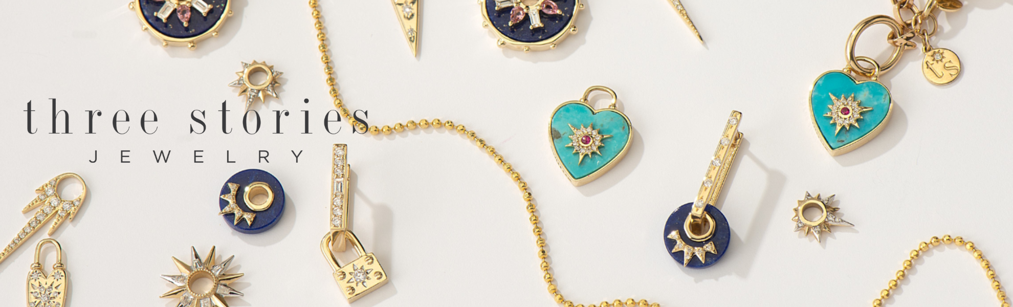 Collection of gold and blue jewelry charms on a white background with 'three stories jewelry' branding.