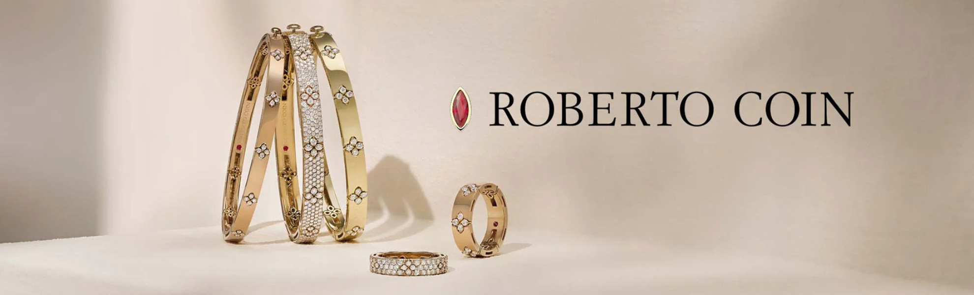 Roberto Coin jewelry on a beige background with the brand name displayed.