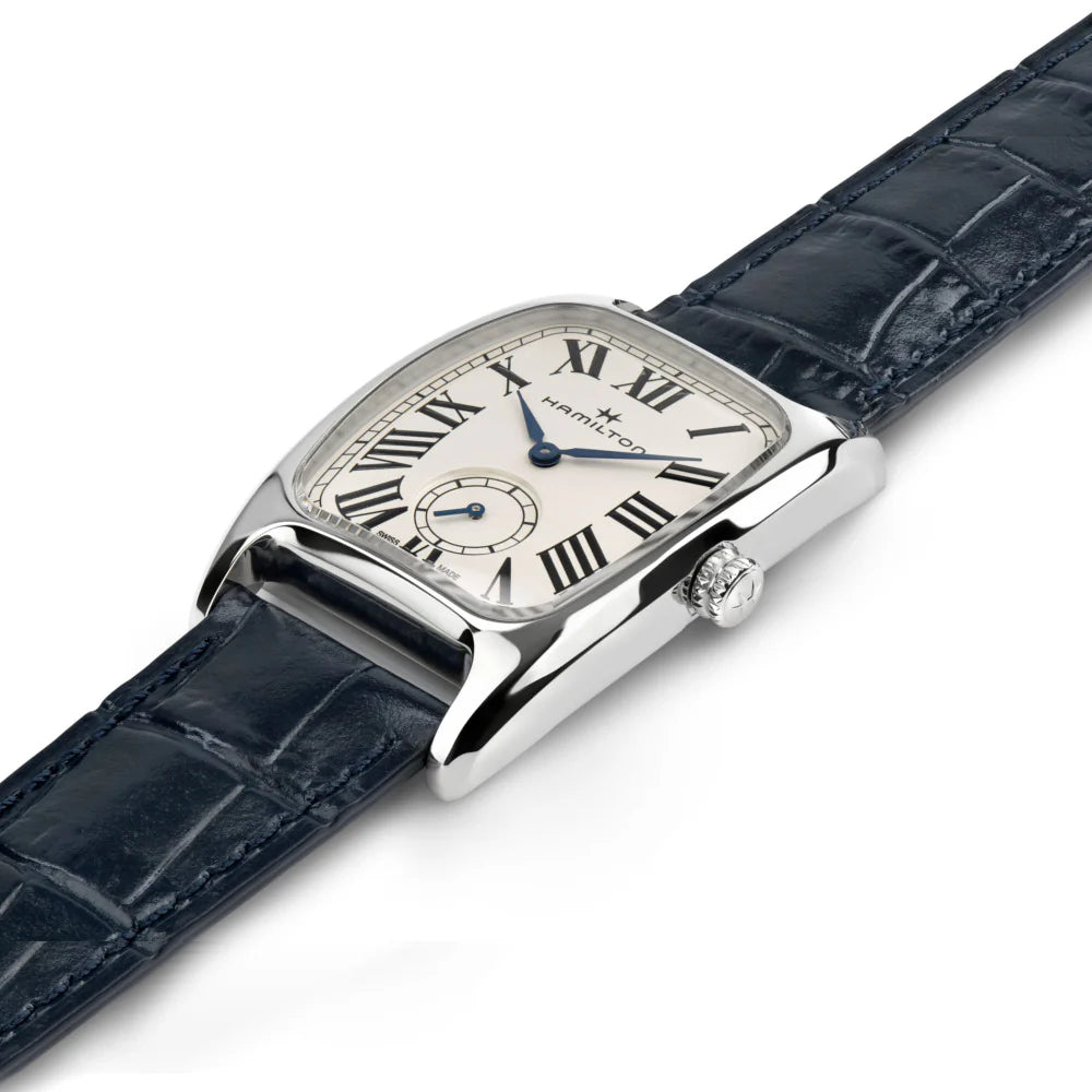 A Hamilton watch with a polished silver-tone case, cream dial with black Roman numerals, and a dark blue alligator leather strap, shown on a white background.