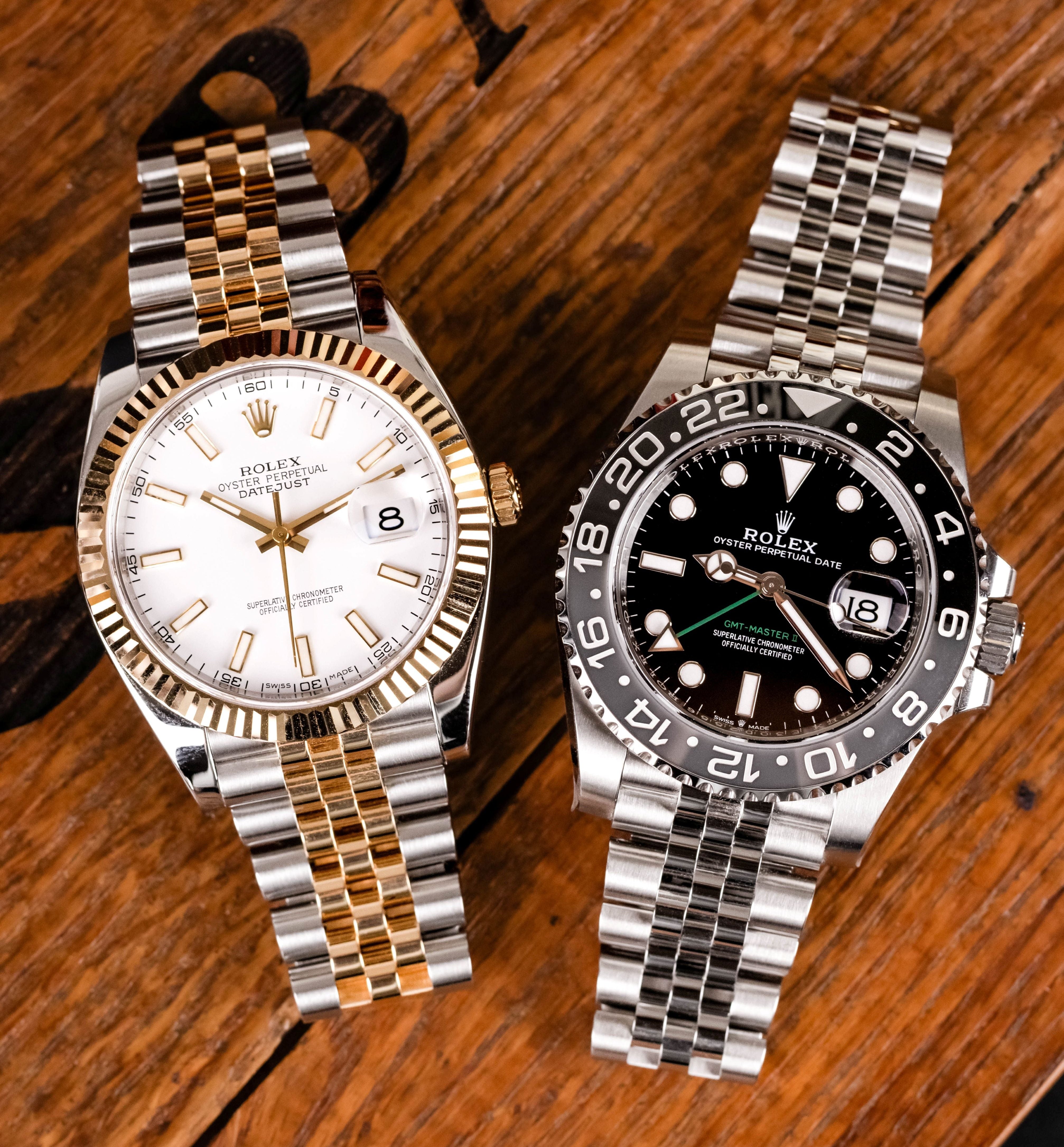 Two Rolex watches on a wooden surface