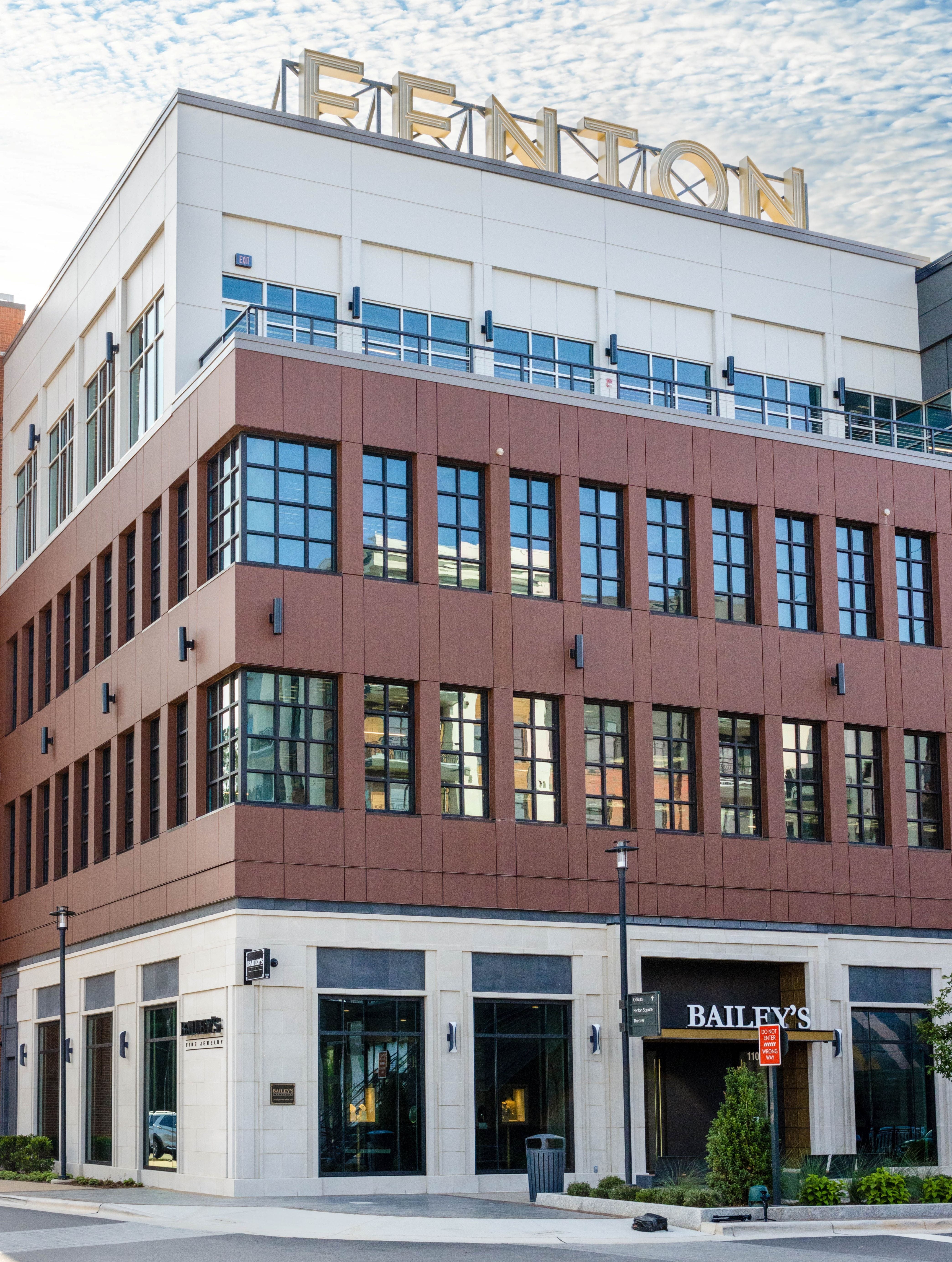 Modern building with 'Fenton' sign on top, featuring glass windows and a brown facade.