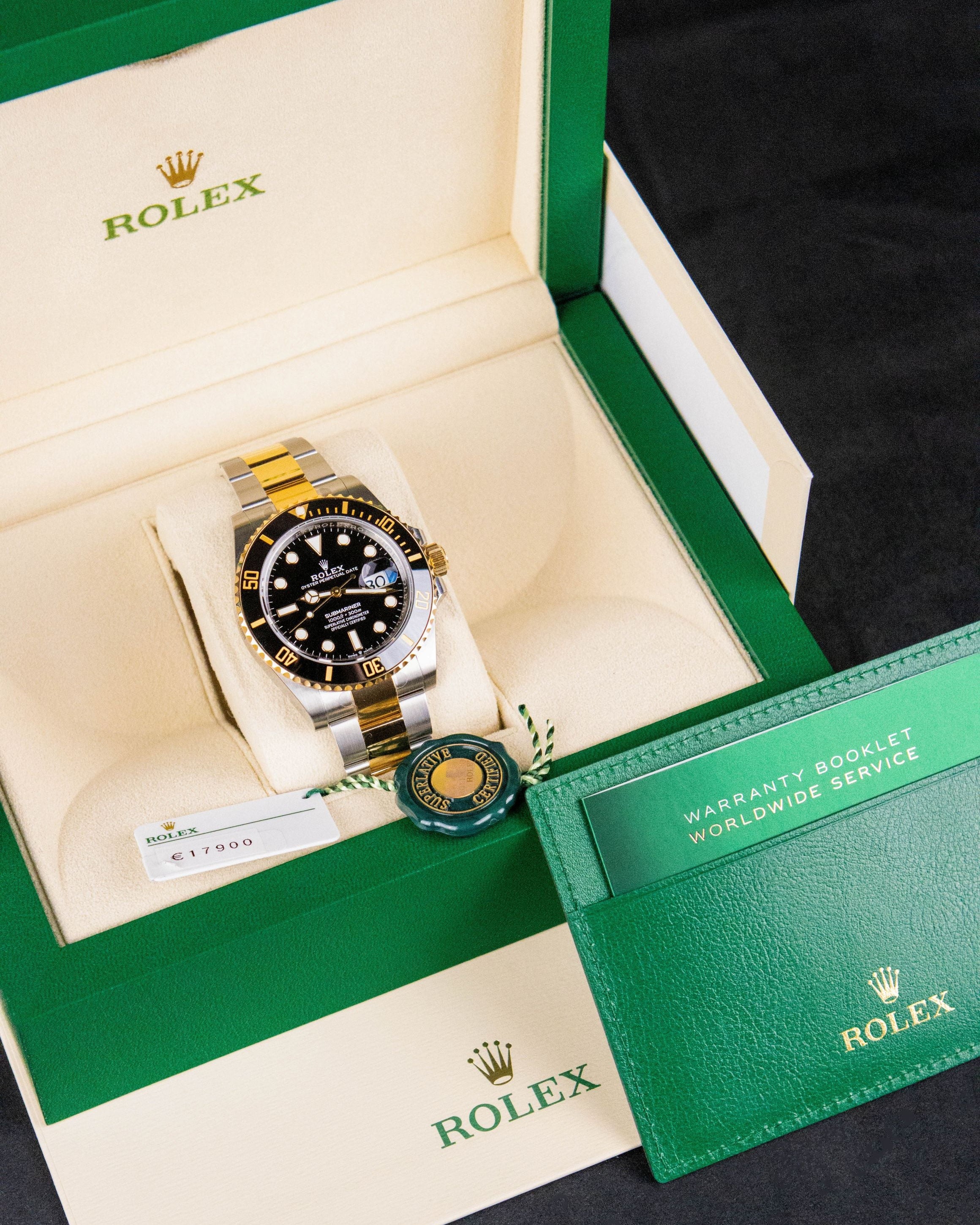 Rolex watch in a green and beige box with a green card on a dark background