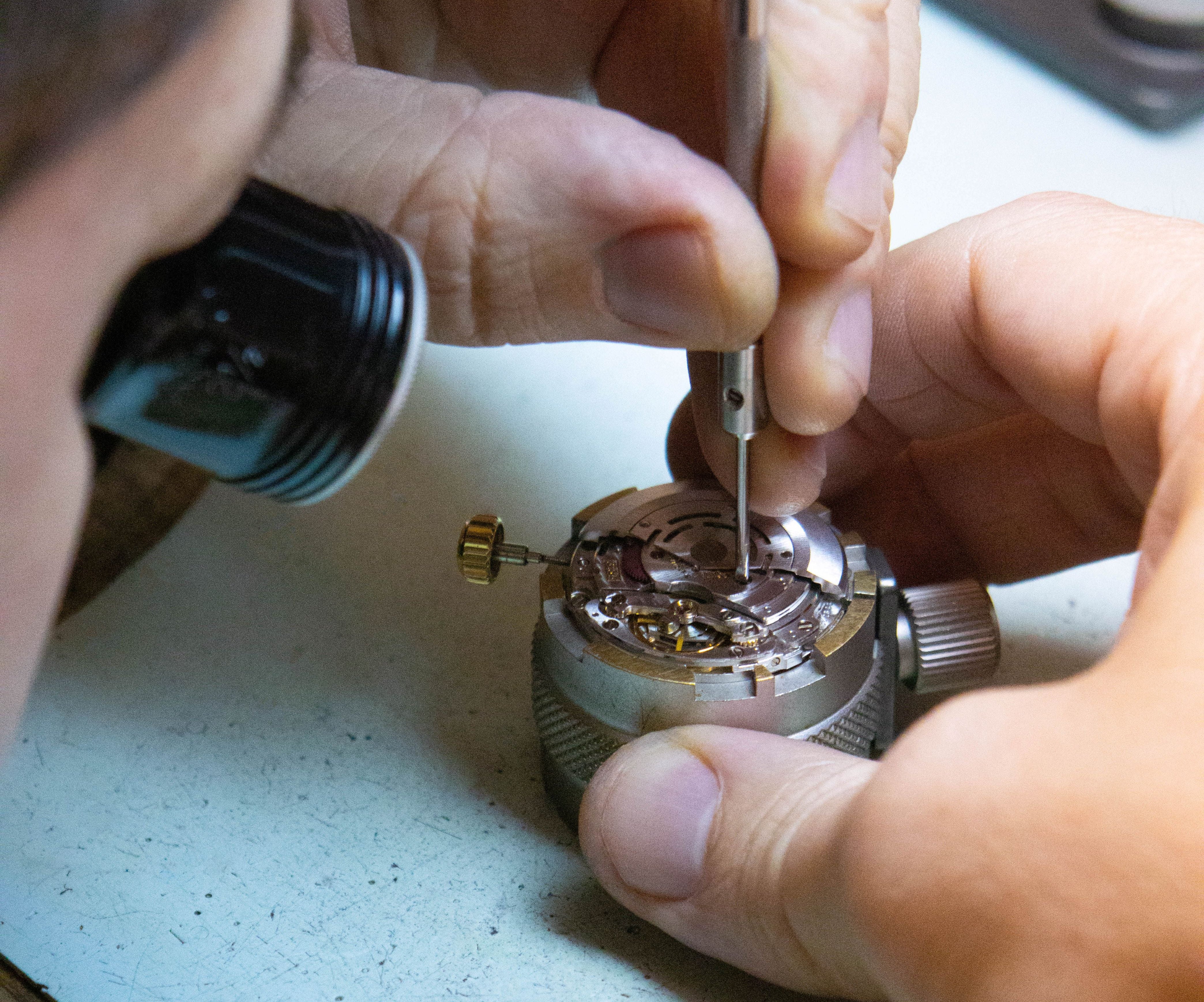 Person working on a watch mechanism with tools