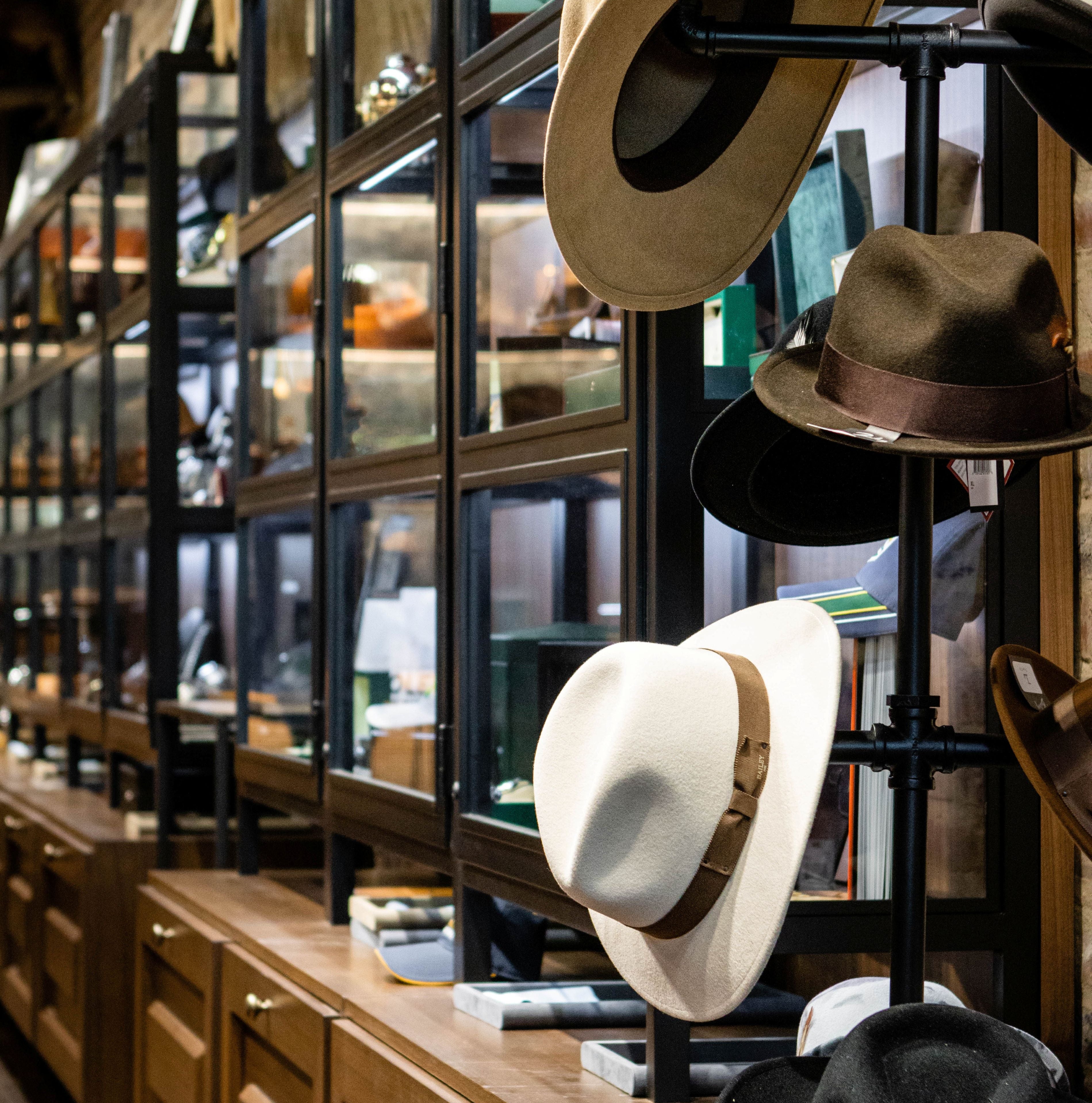 Hats displayed on a stand in a store with bookshelves in the background