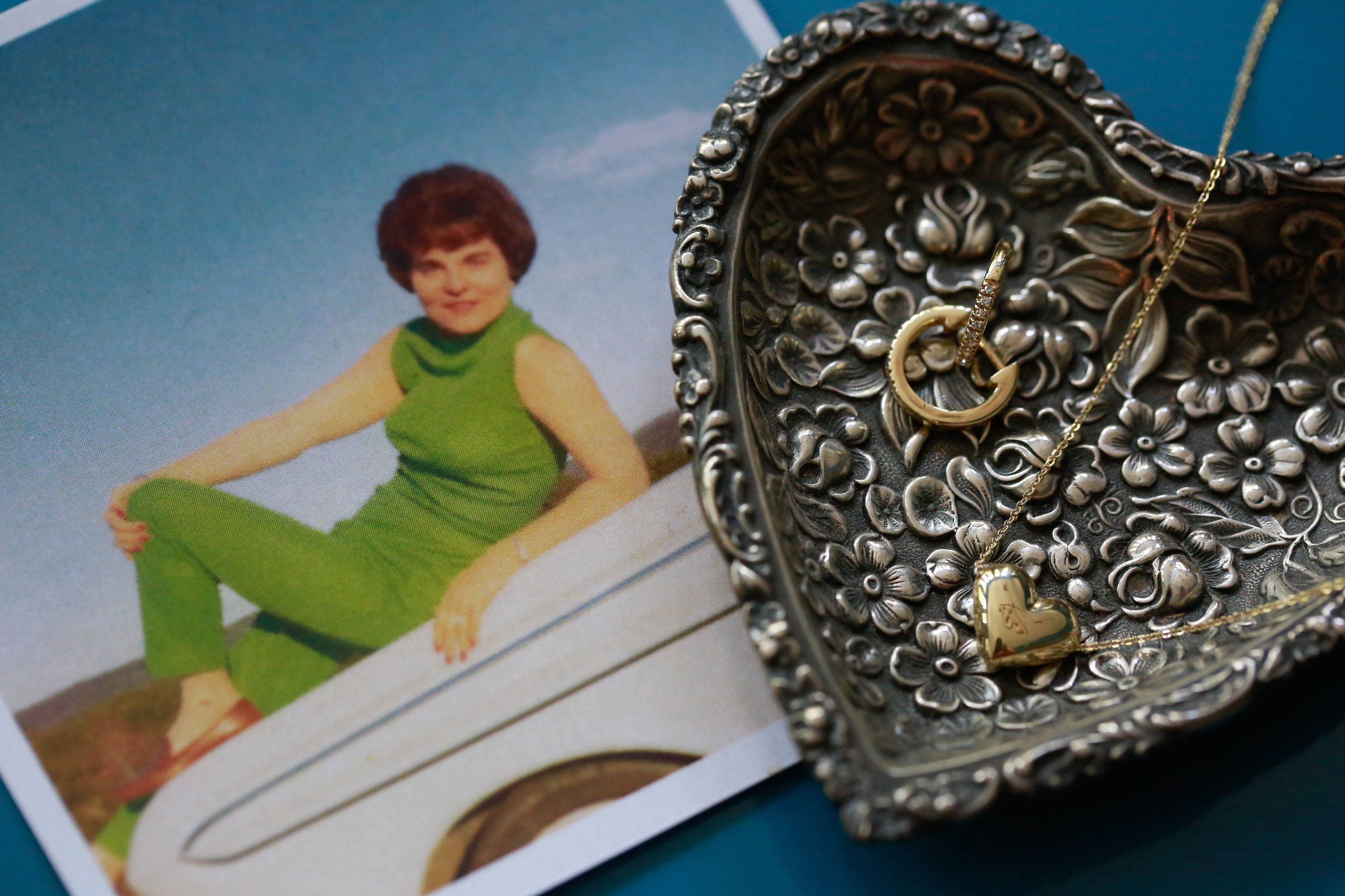 Decorative silver jewelry box with intricate designs on a background of a vintage photo of a woman in a green outfit.