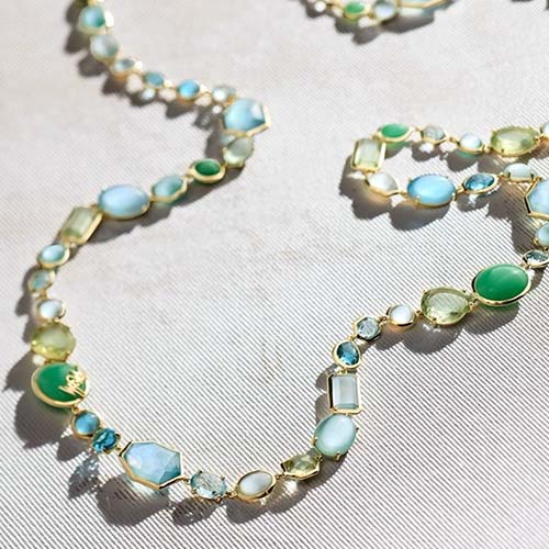 Necklace with green and blue gemstones on a light background