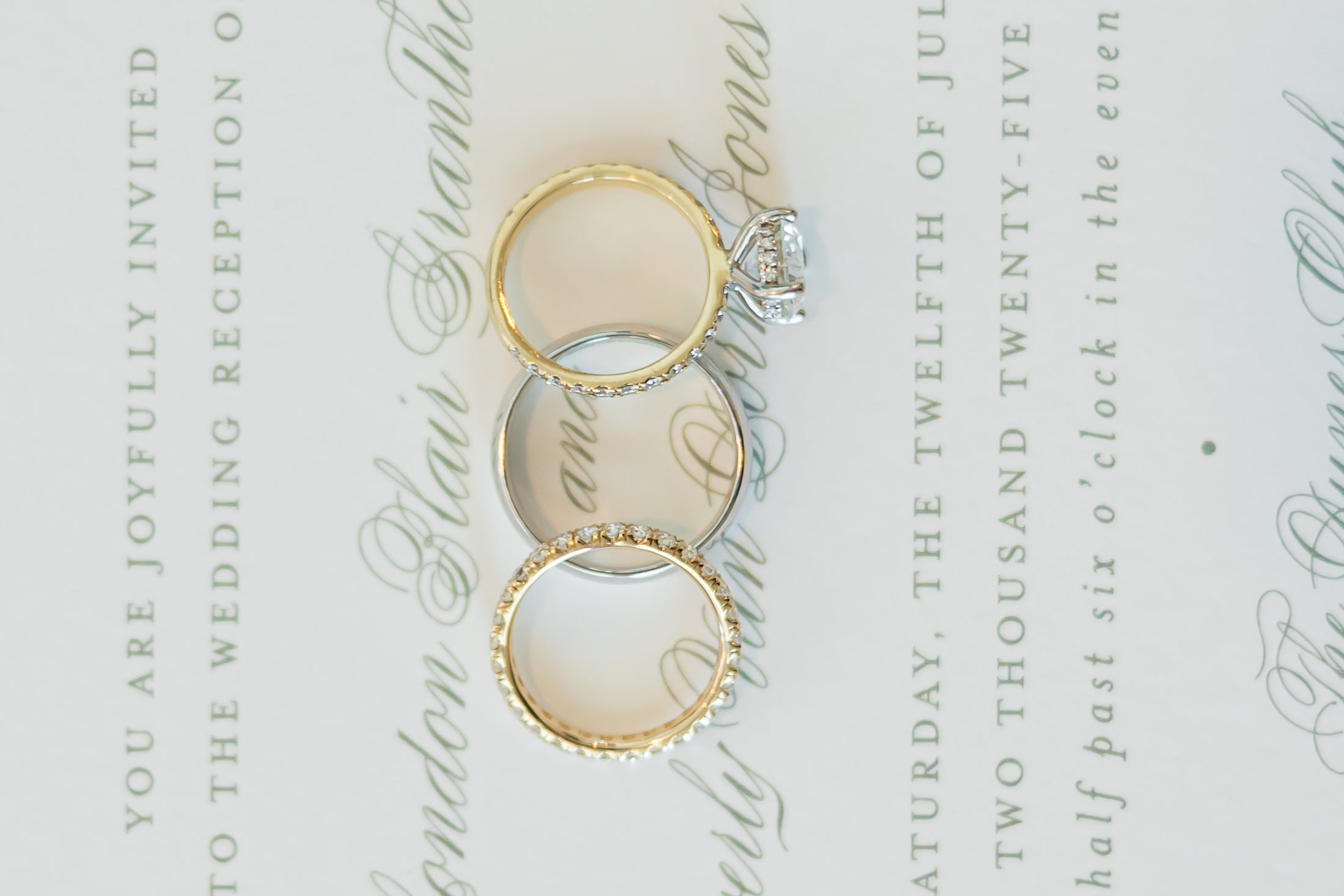 Three gold rings on a wedding invitation with calligraphy