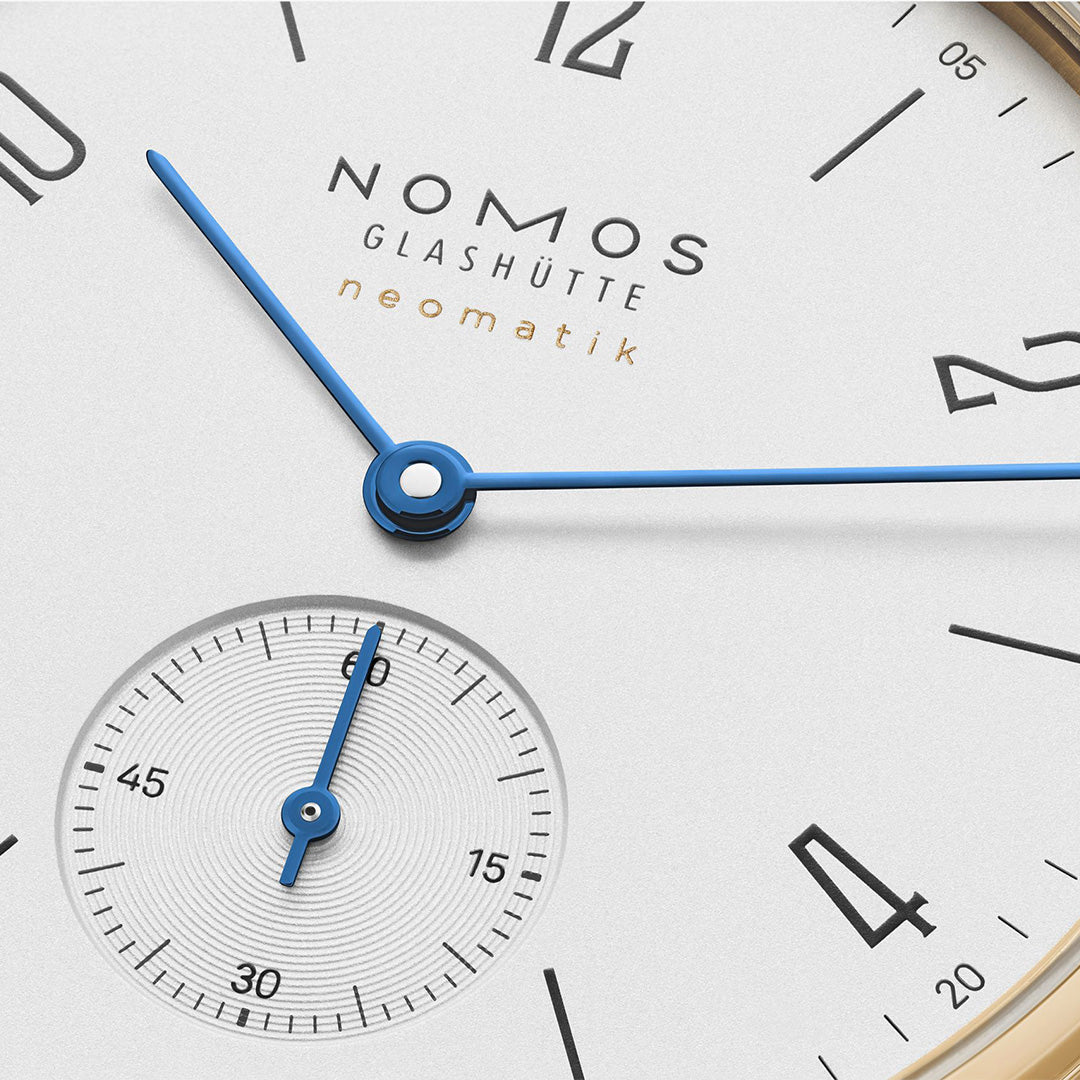 Nomos Glashütte watch face with blue hands on a white background
