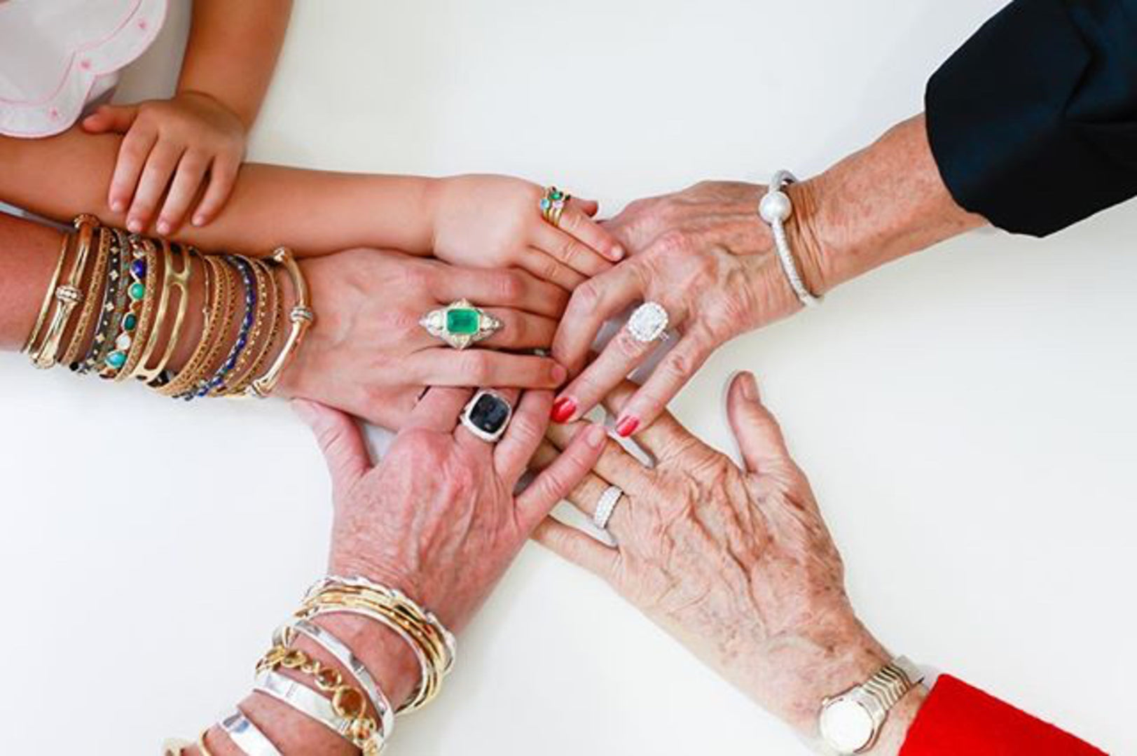 Hands of people with jewelry, including rings and bracelets, on a white background