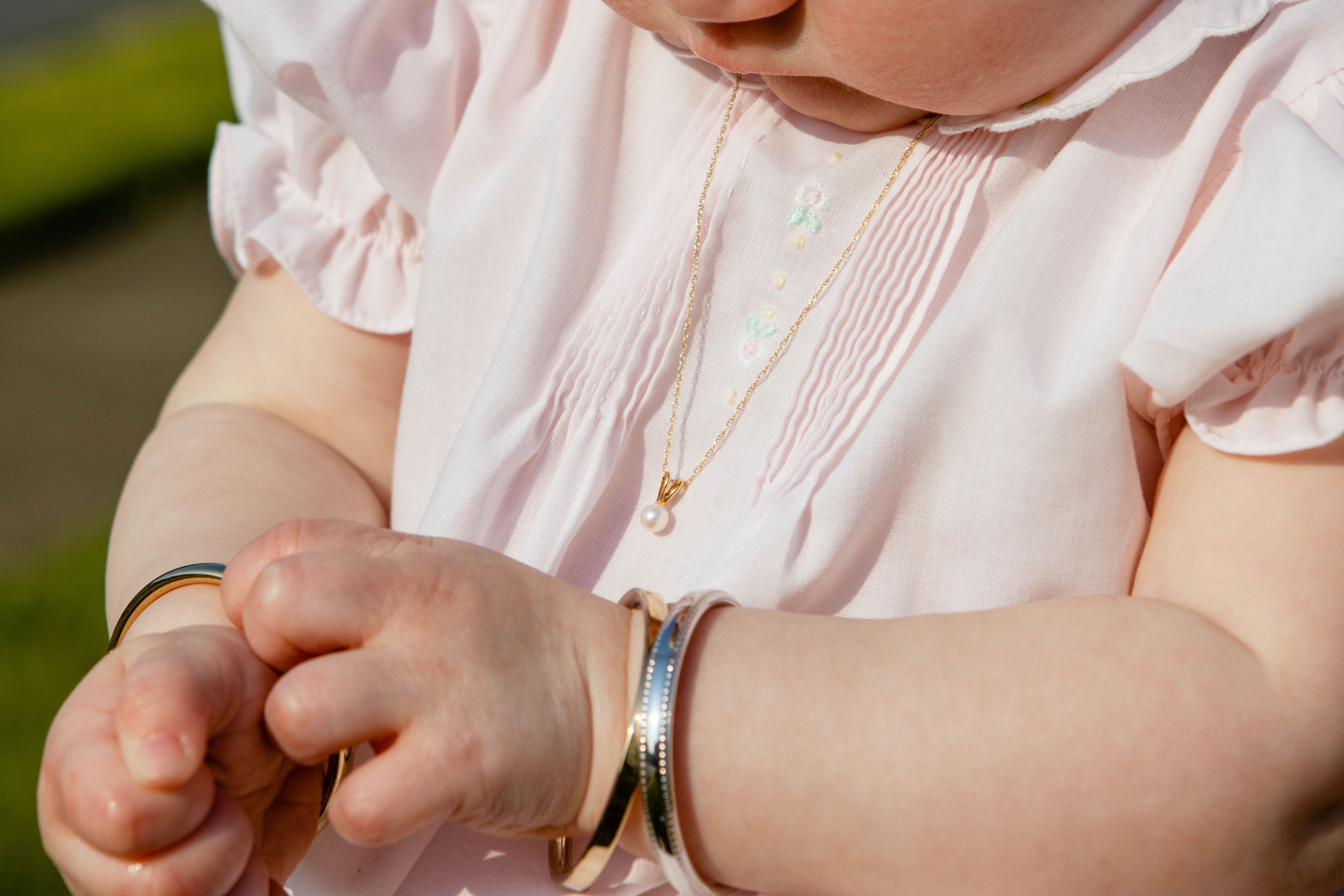 Close-up of a baby's hands wearing gold bracelets with a blurred background