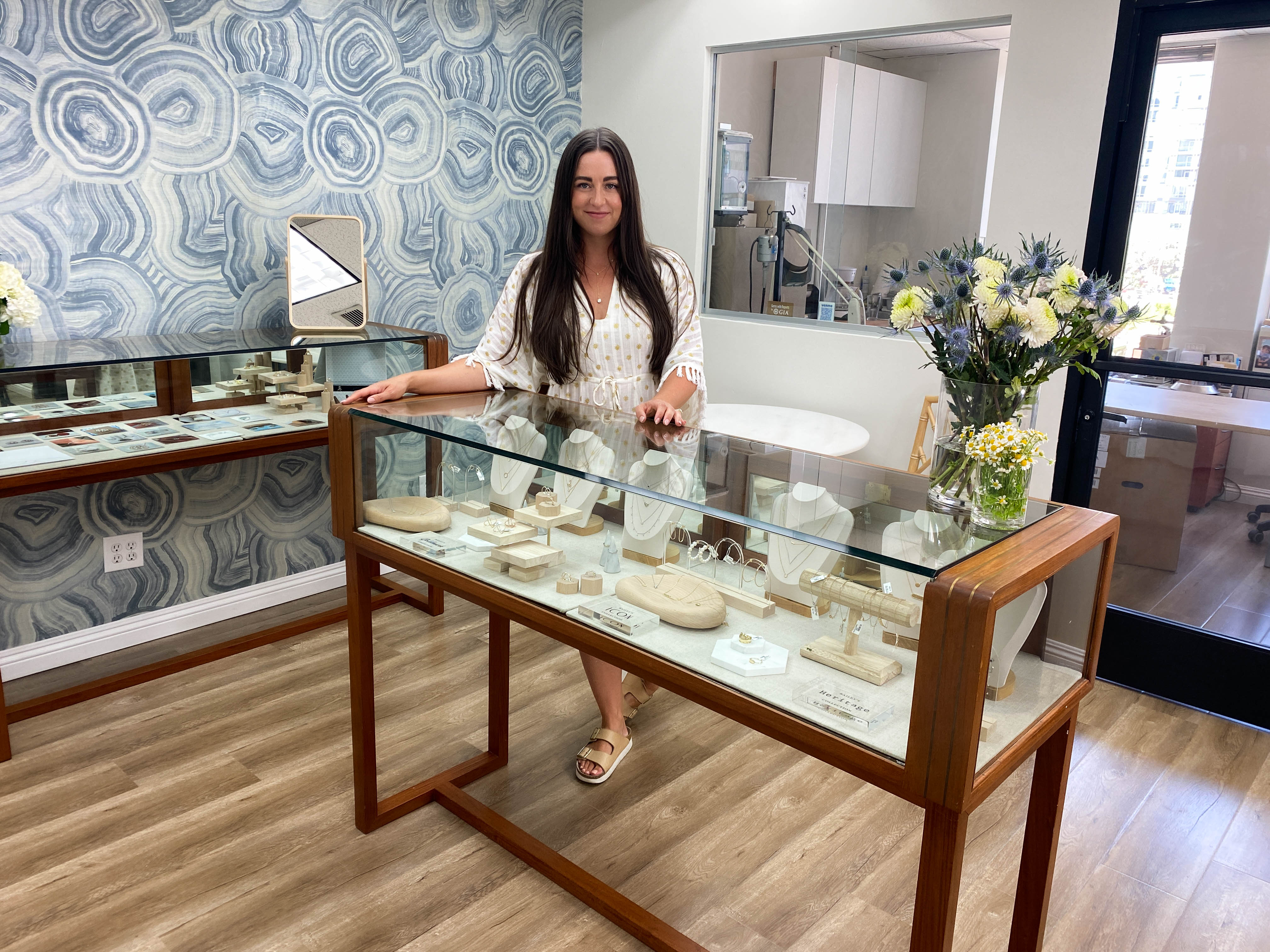 Woman standing in showroom behind glass jewelry display case