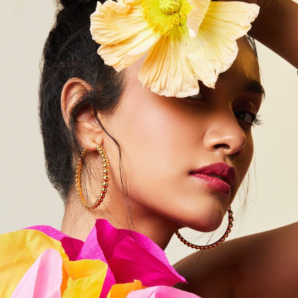Woman with a large yellow flower in her hair against a neutral background