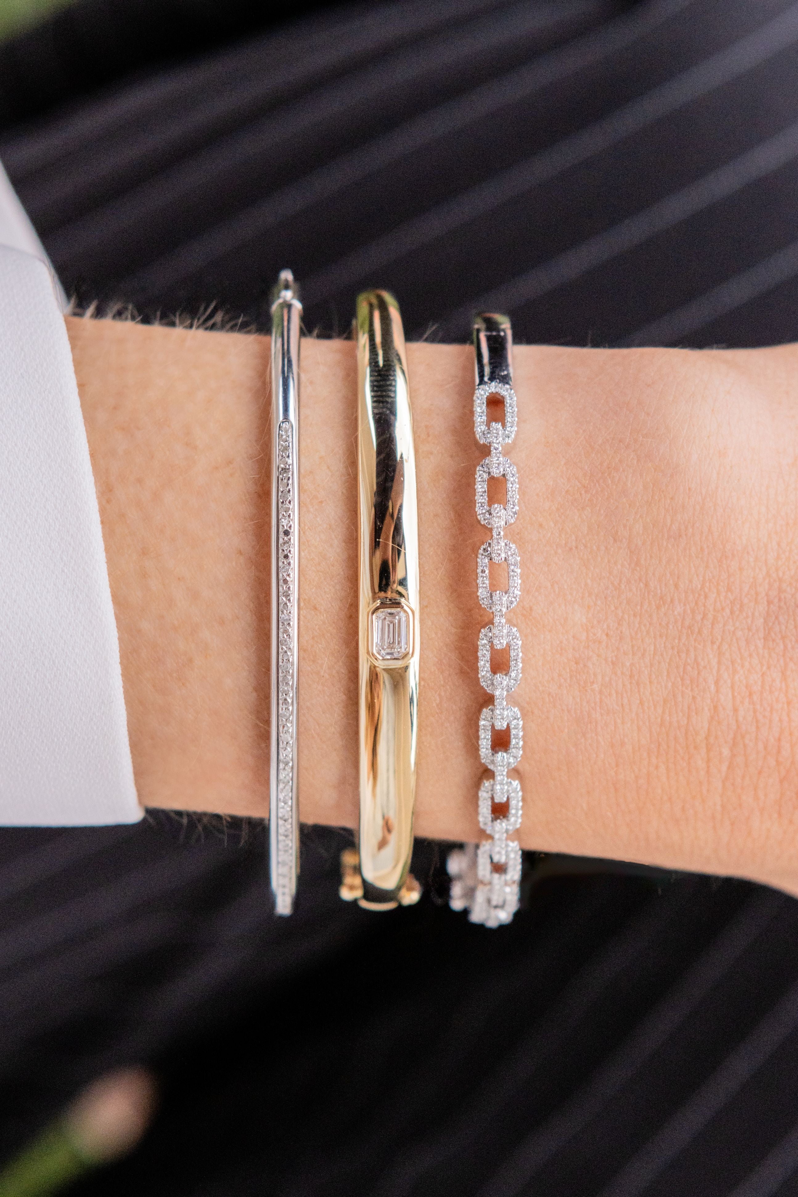 Three bracelets on a wrist against a black background