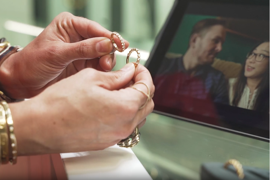 Person holding two rings with a blurred background of two people talking on a tablet