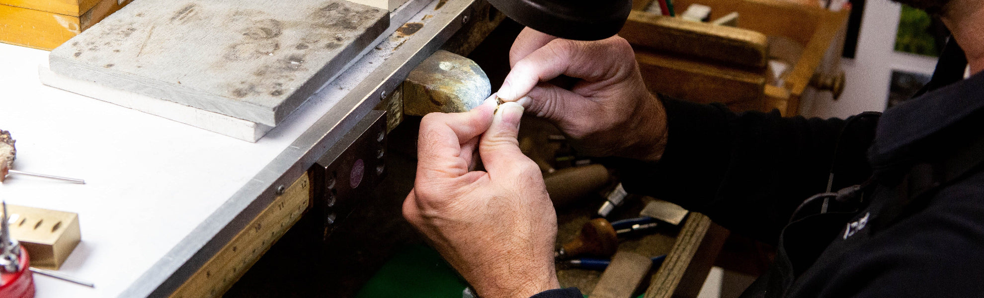 Person working on a piece of jewelry in a workshop setting