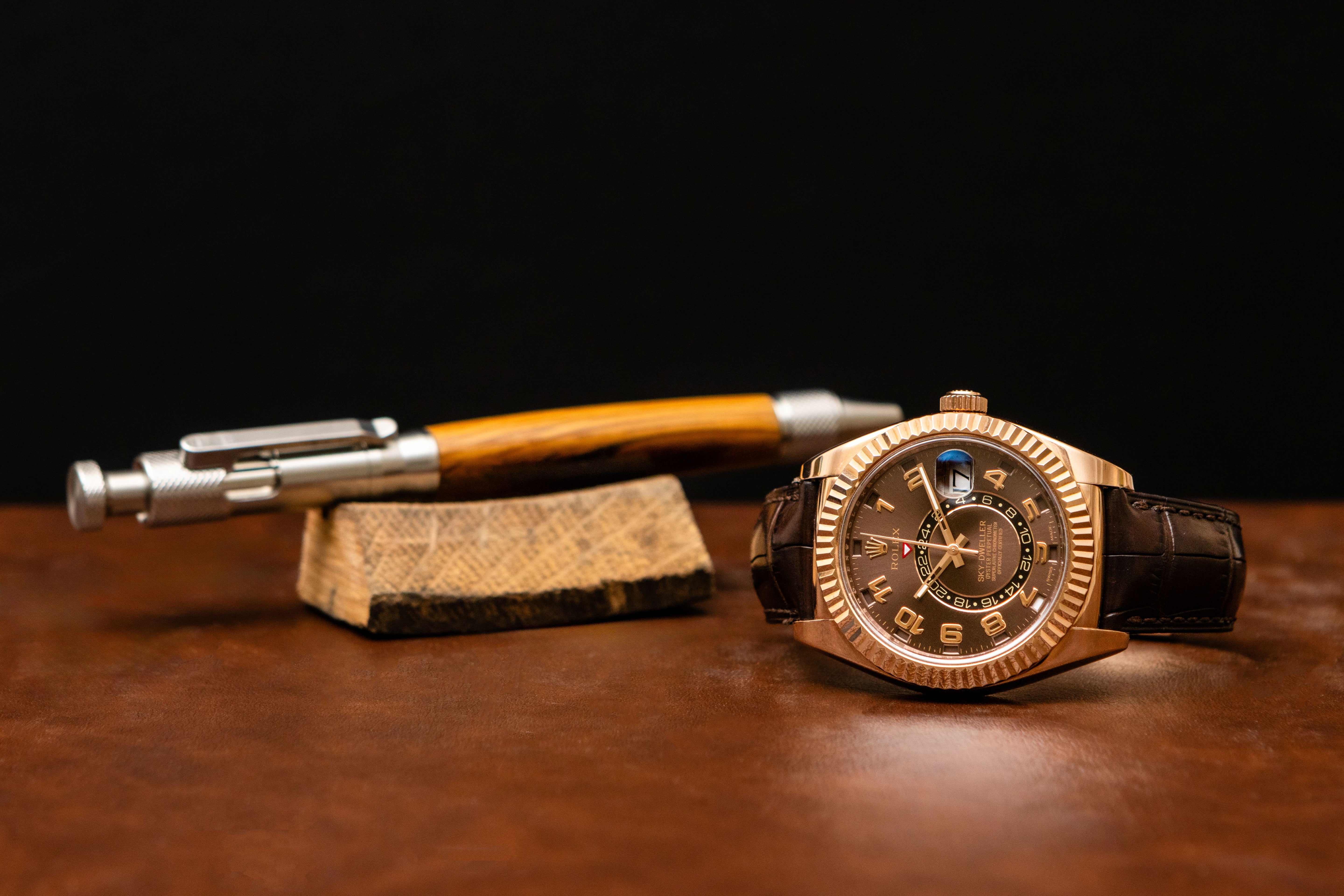 Watch and pen on a dark surface with a black background